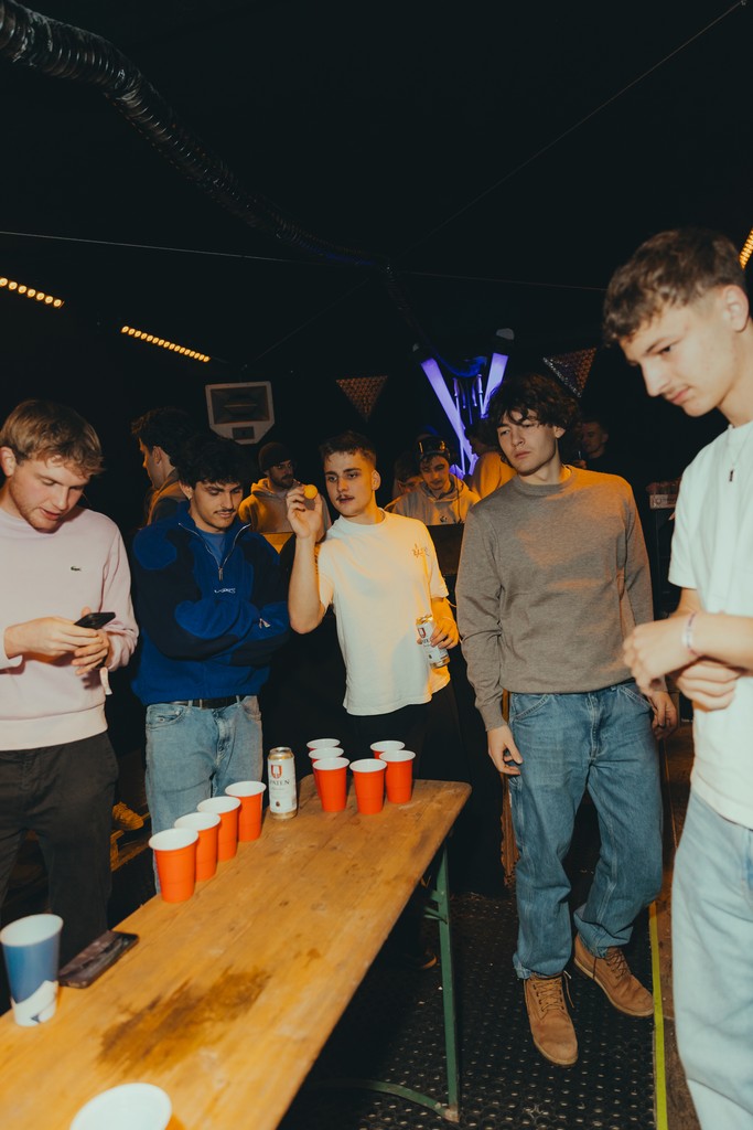 Young adults playing beer pong at a lively night party.