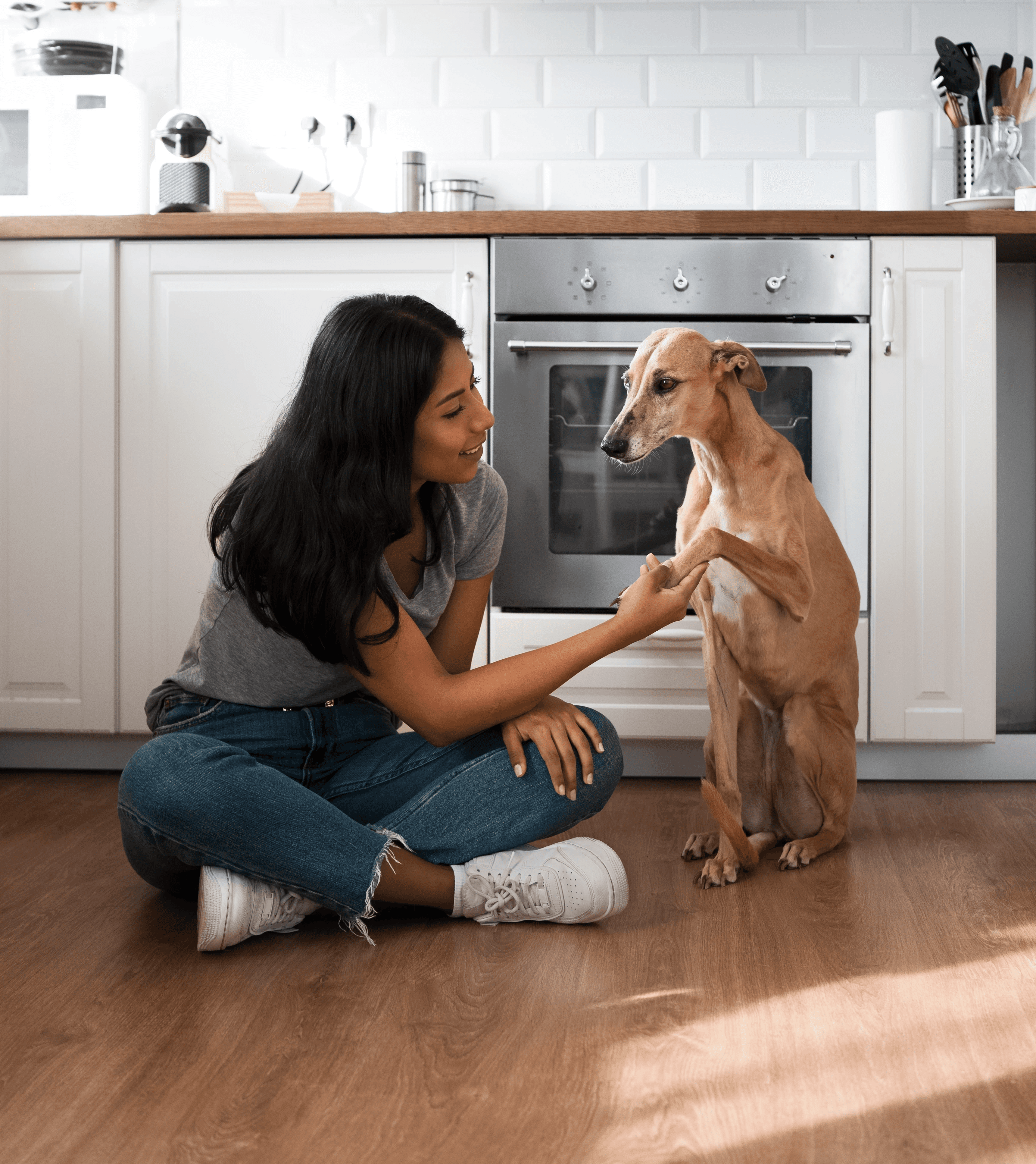 Pet owner sitting on hybrid flooring with her dog in a Brisbane kitchen, showing a surface that handles spills, muddy paws, and daily wear without fuss.