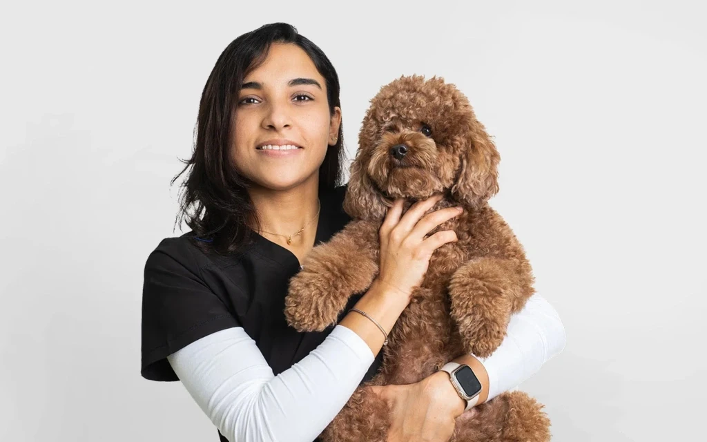 Veterinarian Dr. Aya Maher providing expert care to a white dog at Noble Vet Clinic.