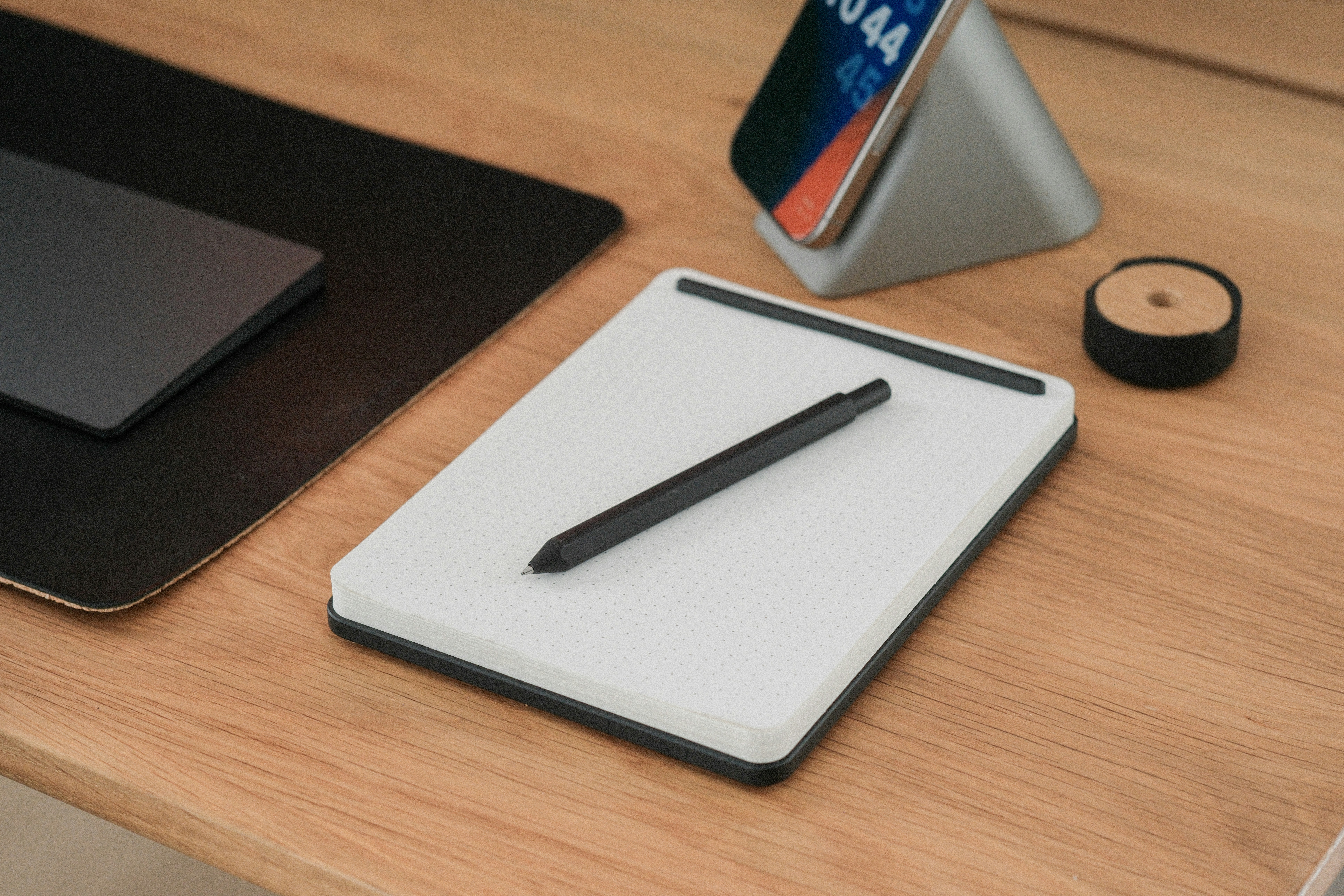 A pen, tablet, and phone on a desk.