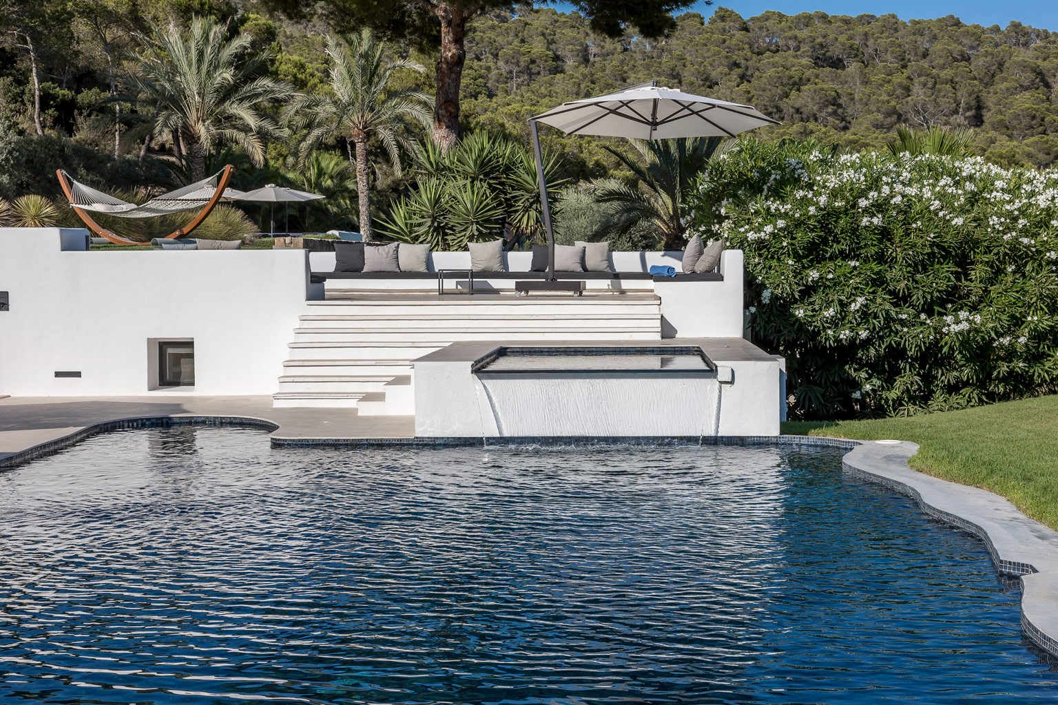 Pool edge with terrace steps, sun loungers and Mediterranean landscaping detail.