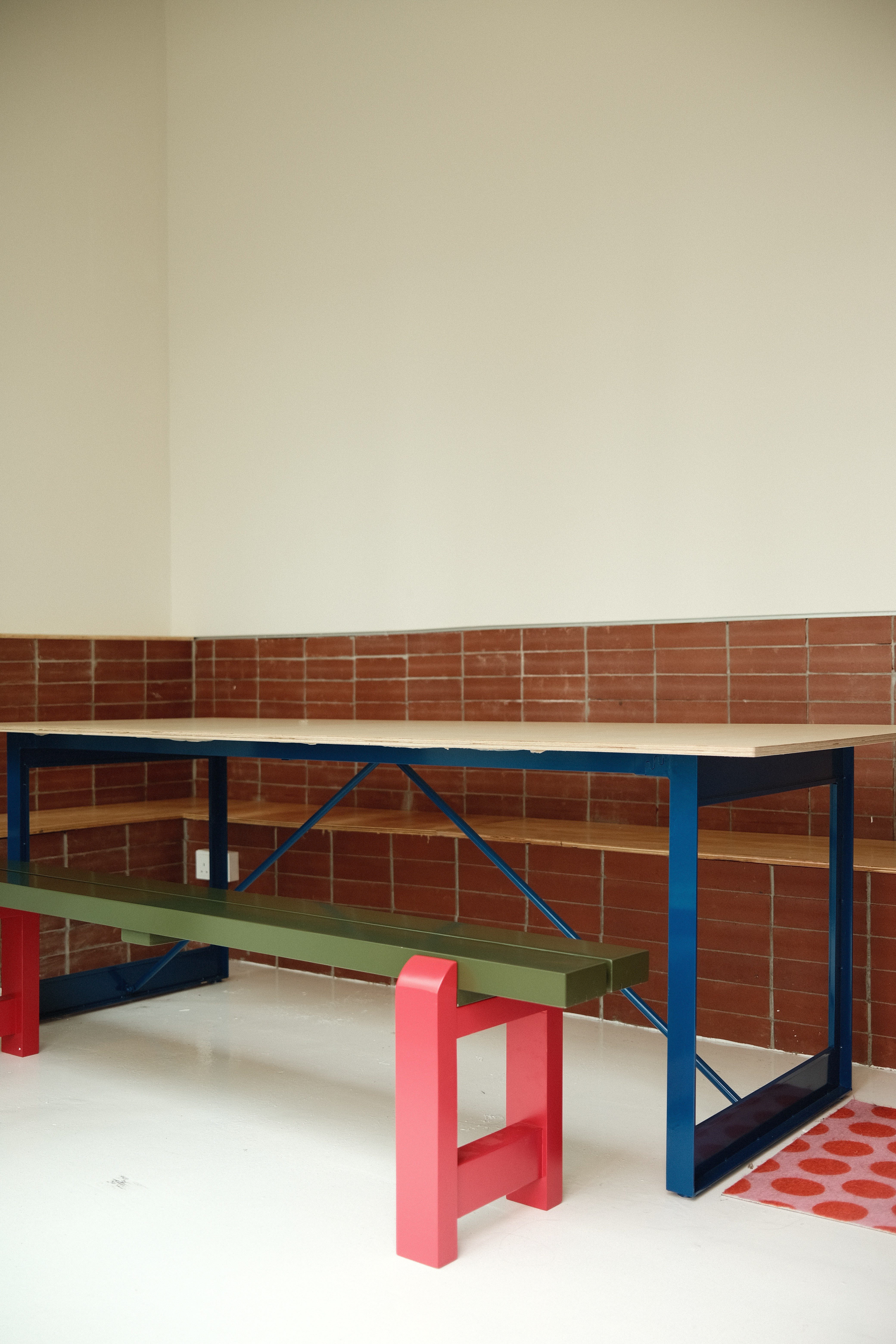 Playful, colour-blocked furniture brings character to this communal seating zone, set against textured brick walls for a bold yet inviting atmosphere.