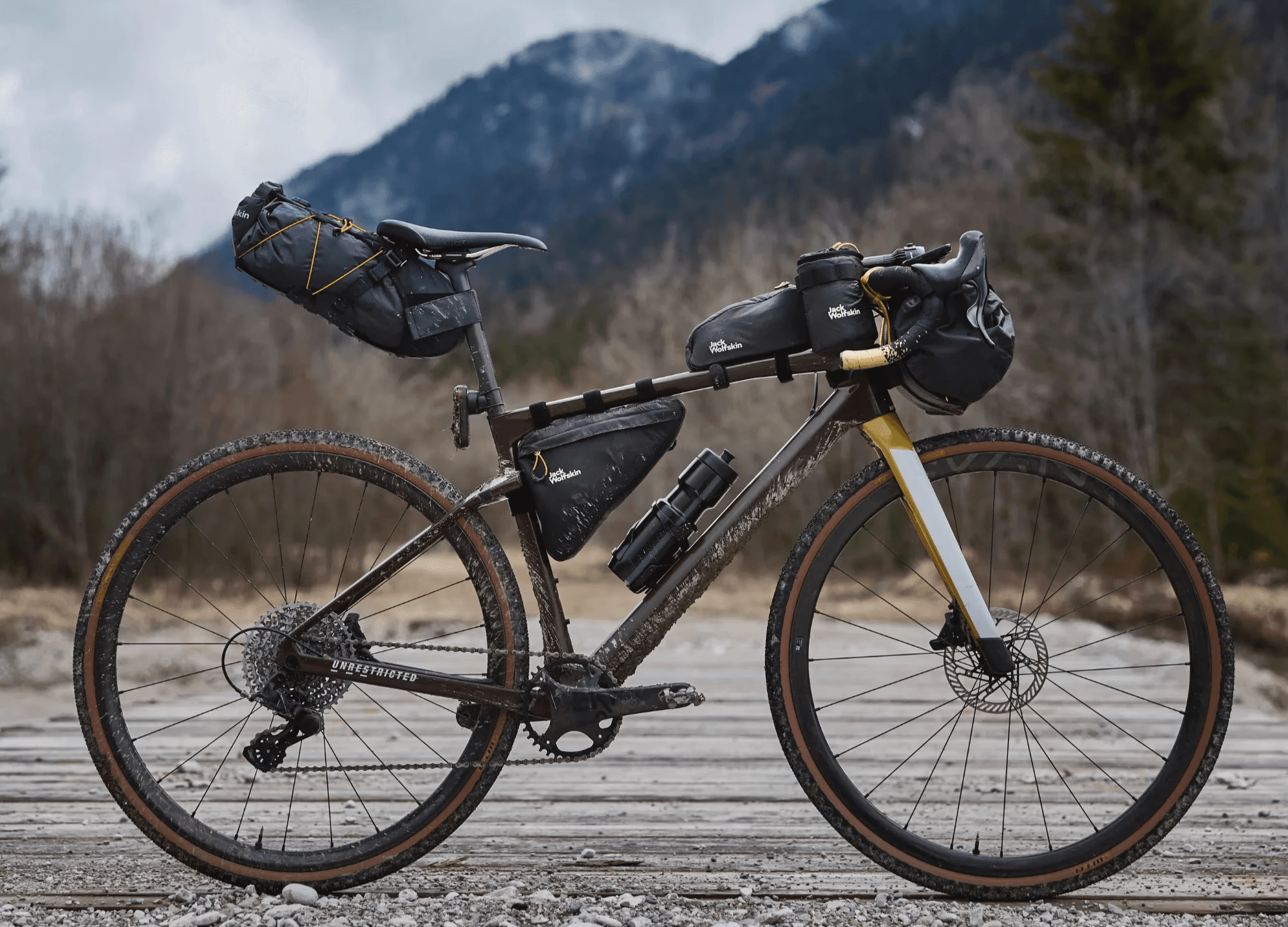Outdoor product photography of a fully equipped bicycle with bags and accessories, set in a natural environment.