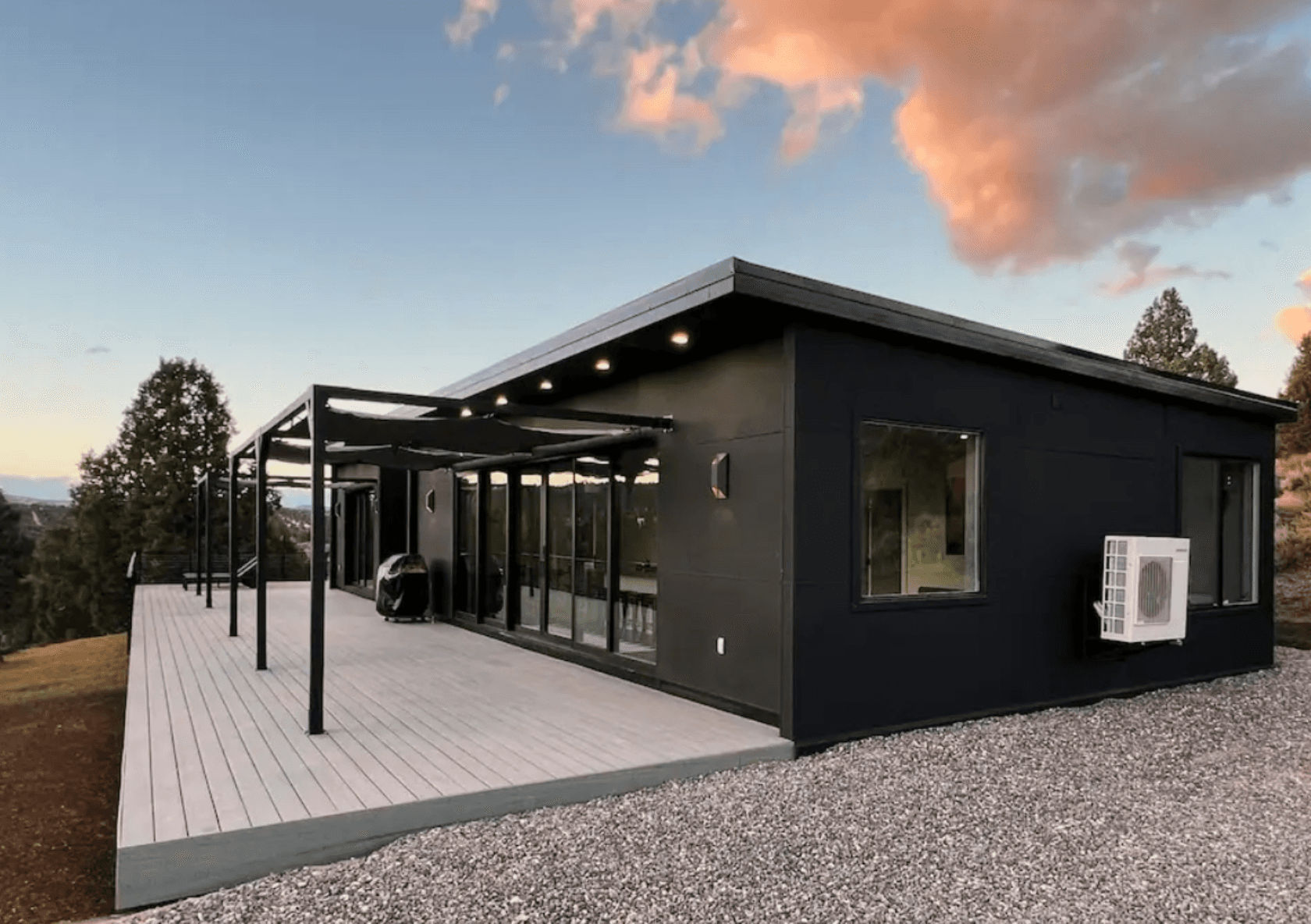 Large modular home with a deck at dusk in a semi arid region.