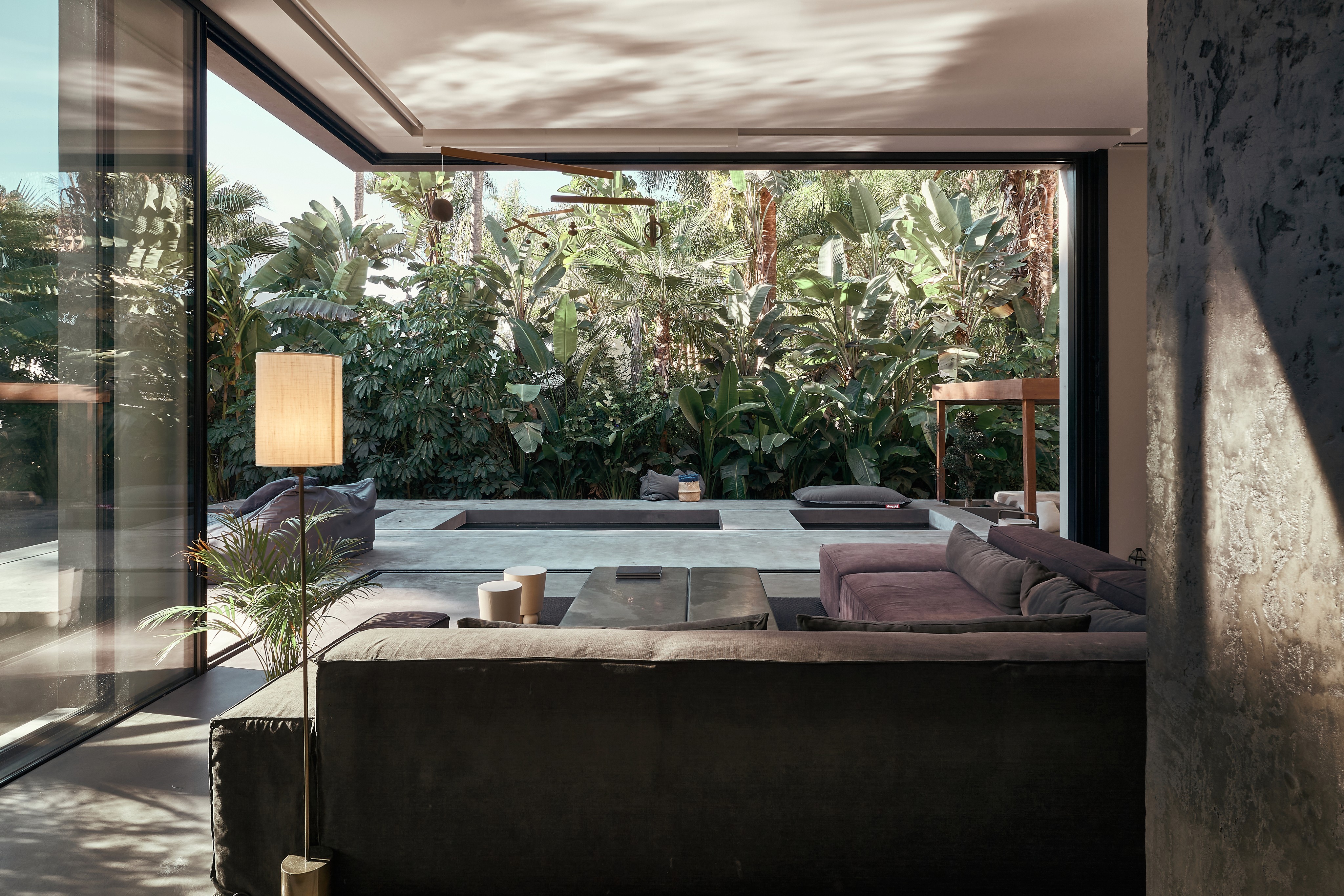 Gråhanå luxury villa interior — open living space merging indoor and outdoor environments with lush tropical vegetation, minimalist furniture, and natural light, expressing Astrophat Studio’s conscious approach to architectural and hospitality branding.