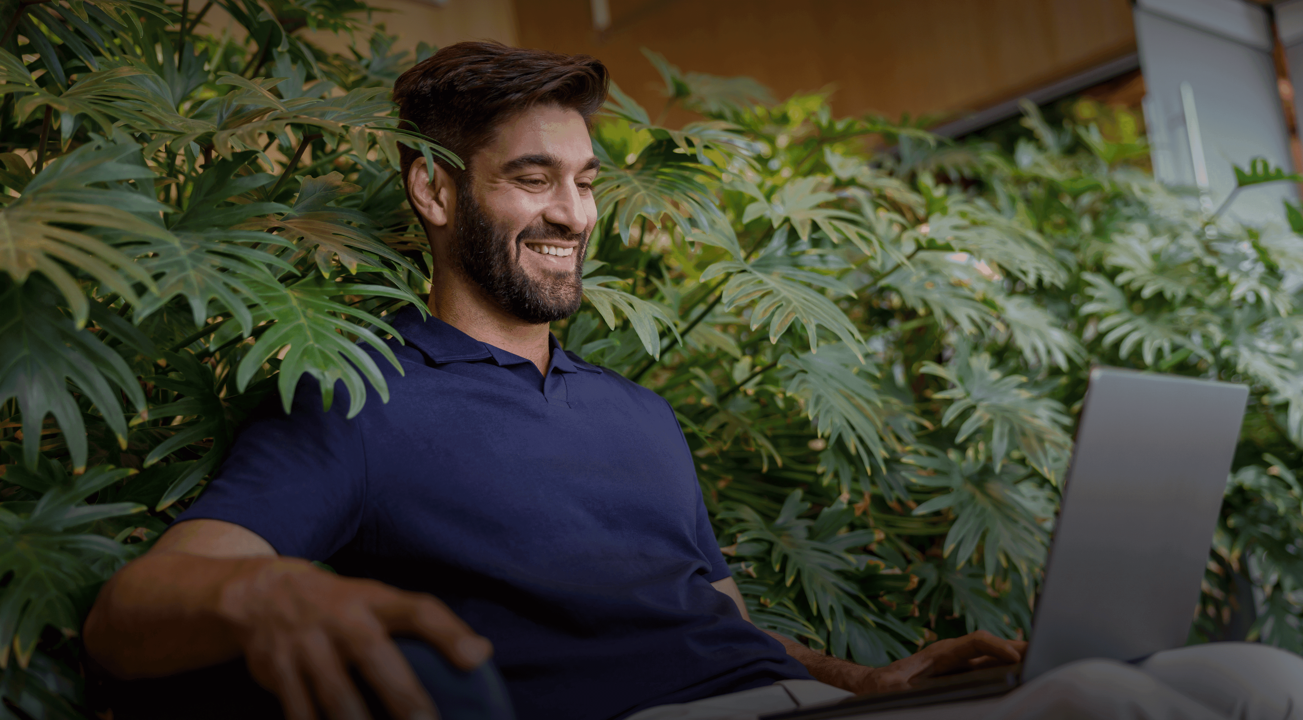 Young man in blue shirt smiling at his laptop