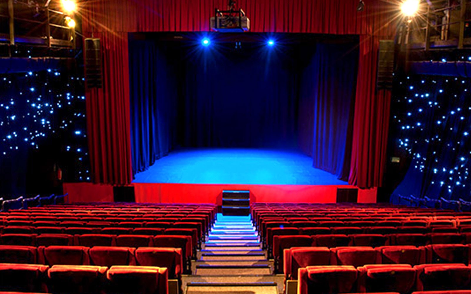 Seville Flamenco Theatre stage with red seats and blue lighting.