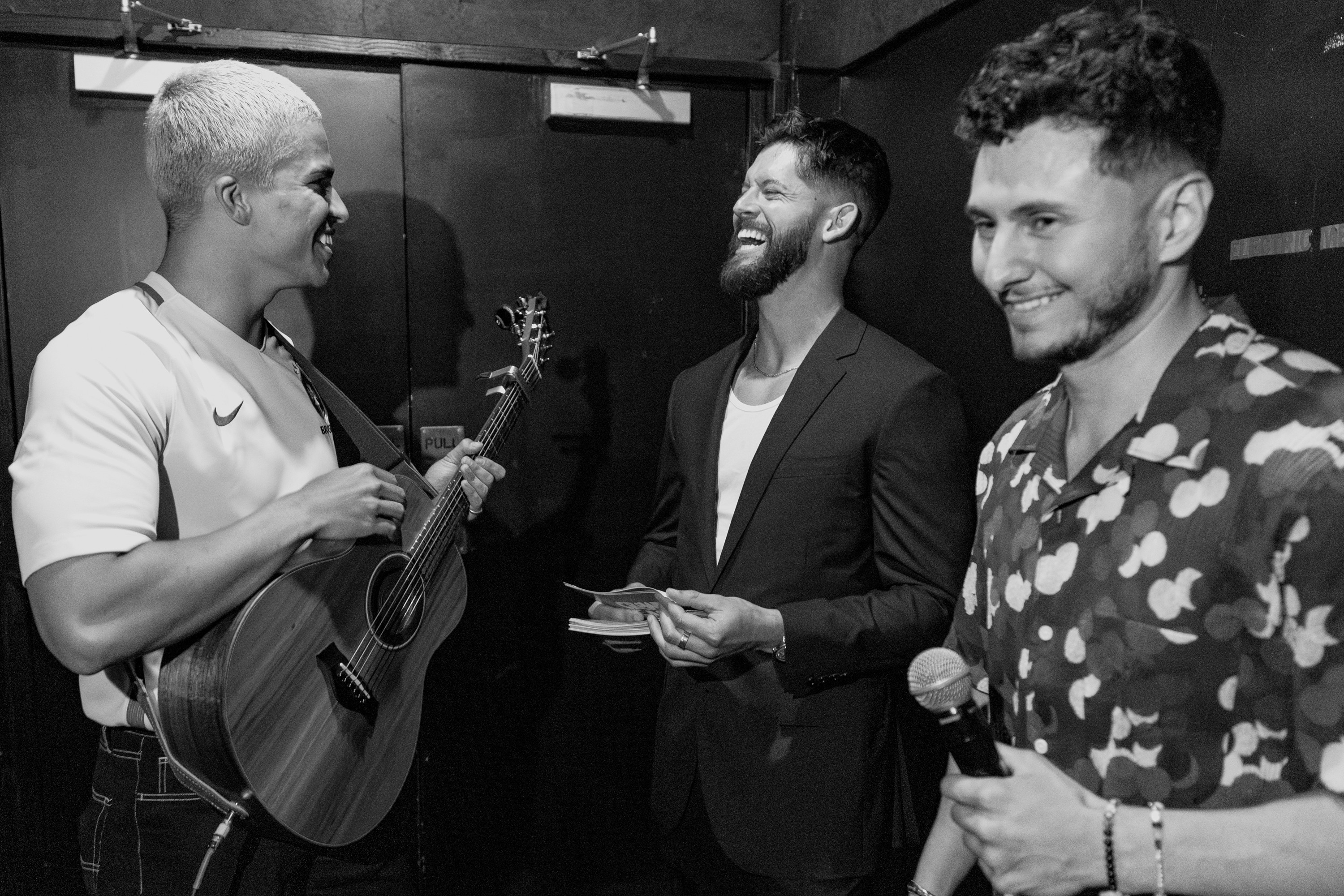 Black and white photo of two people looking at a computer screen with papers on wall