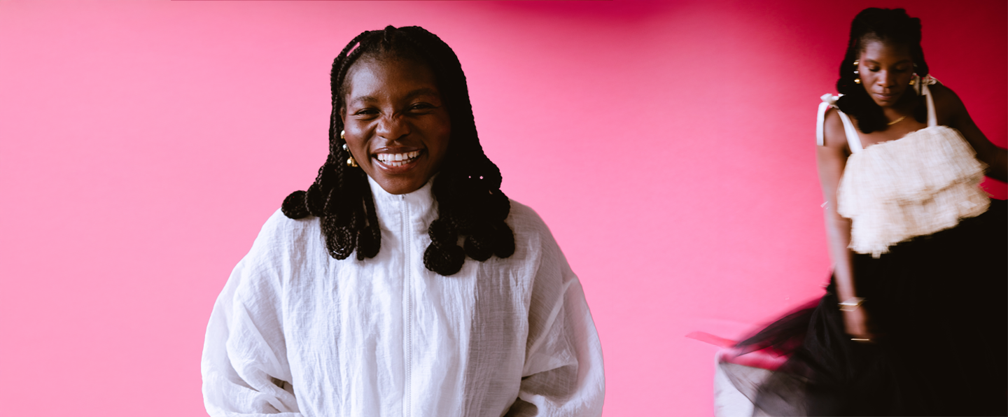 Dali Adekunle sitting and smiling and in the background dancing with pink and red wall to connect with