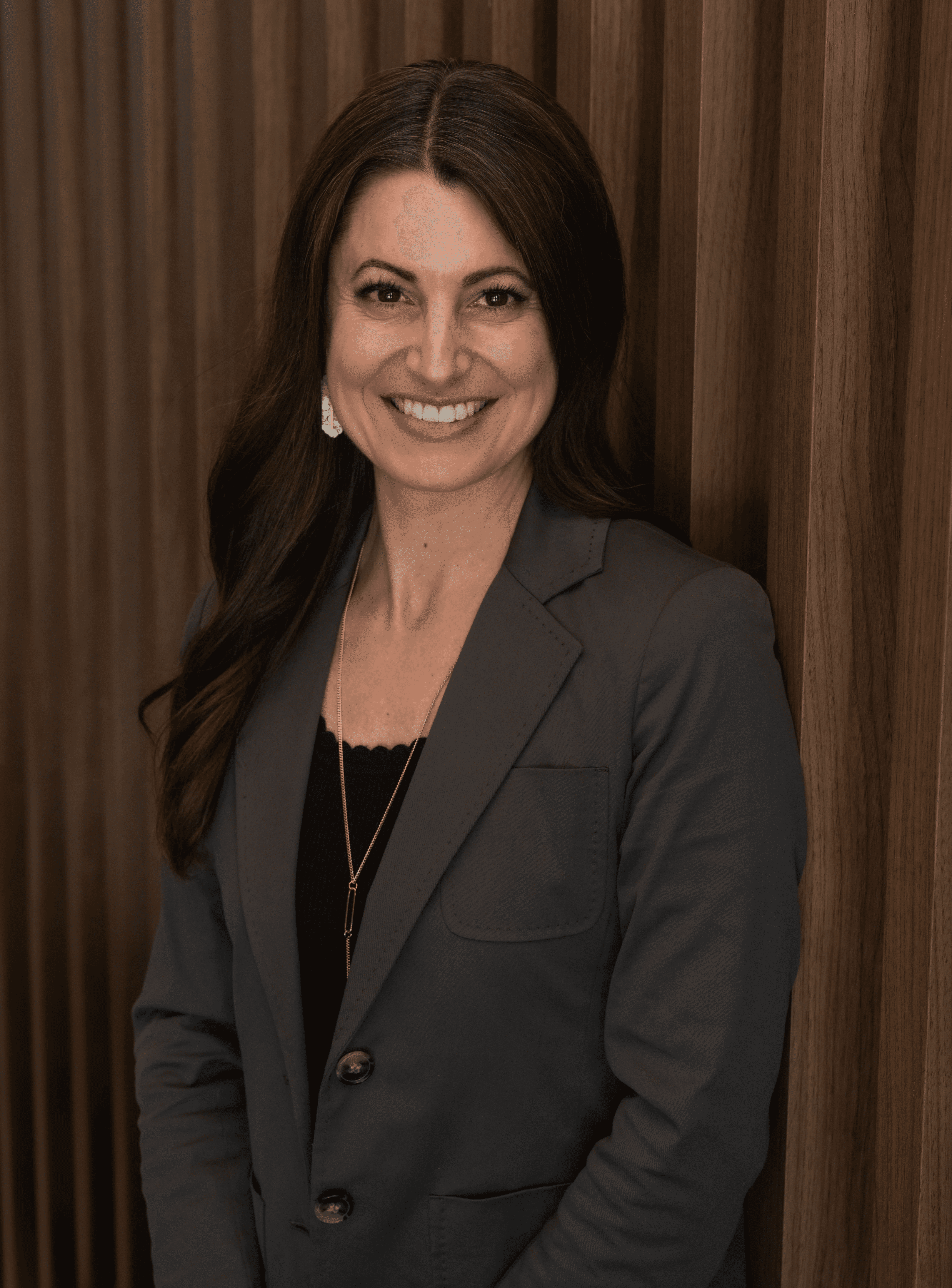 Portrait of a woman in a beige blazer with red lipstick, neutral background.