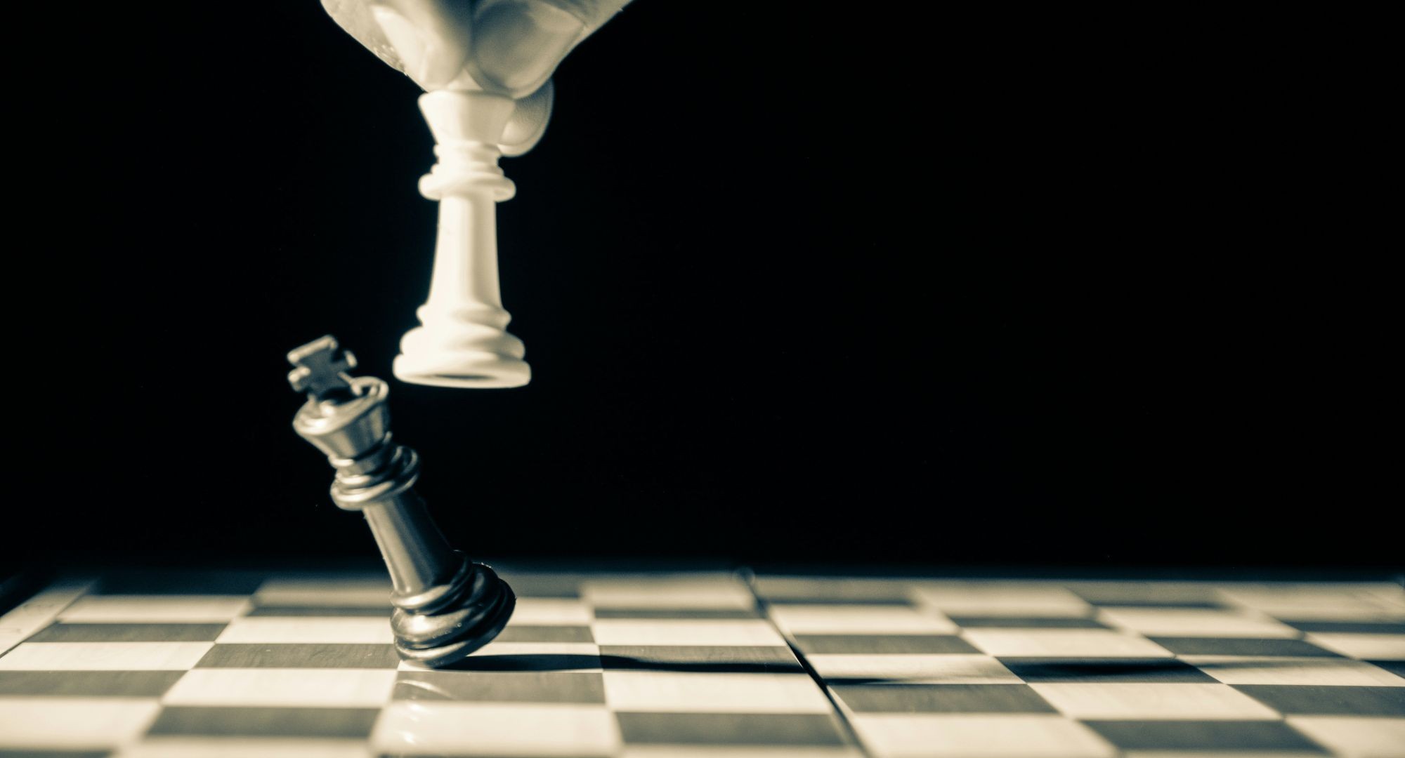 rei branco derrubando rei preto numa tabuleiro de xadrez vazio