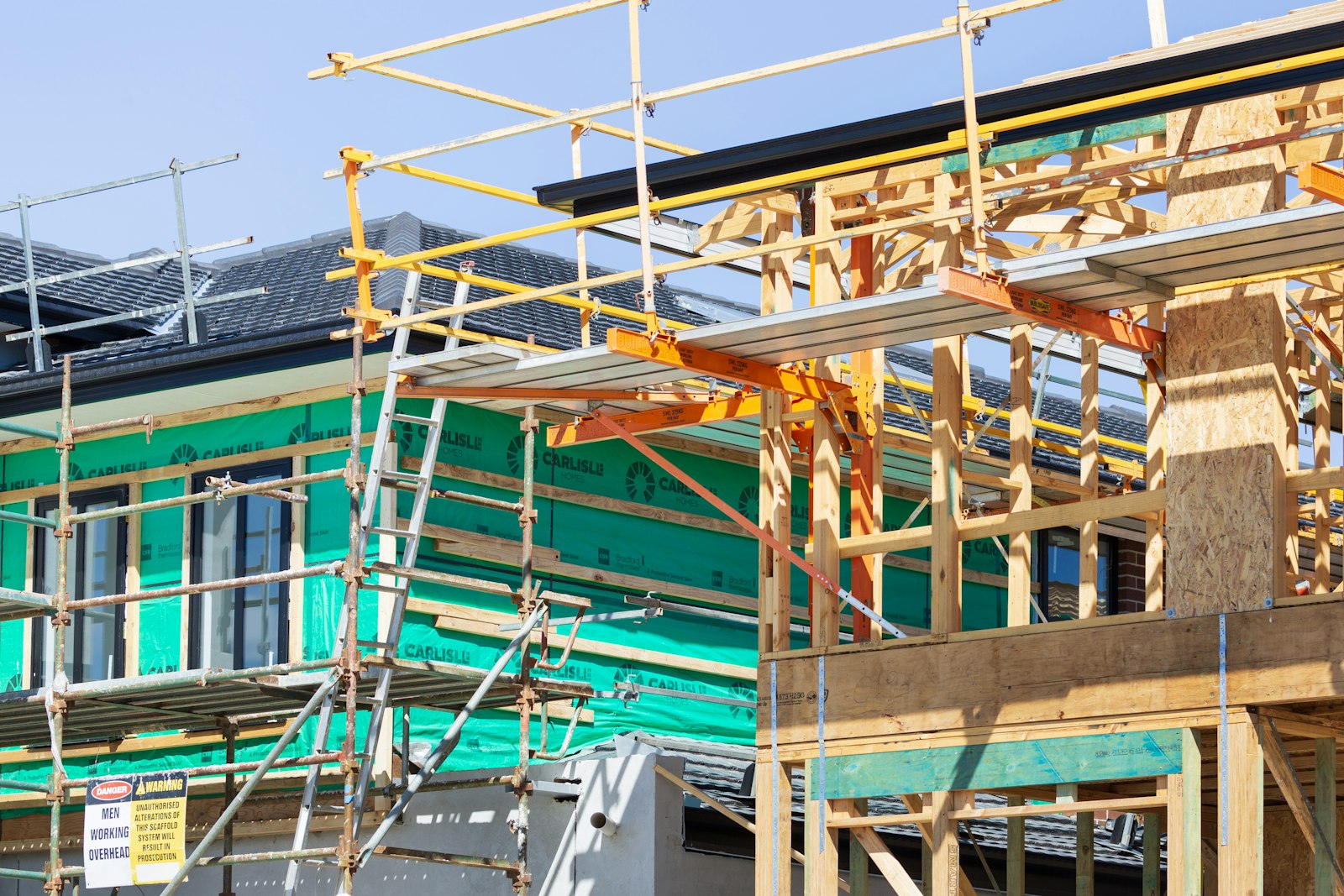 Timber-framed house under construction with scaffolding on the roof