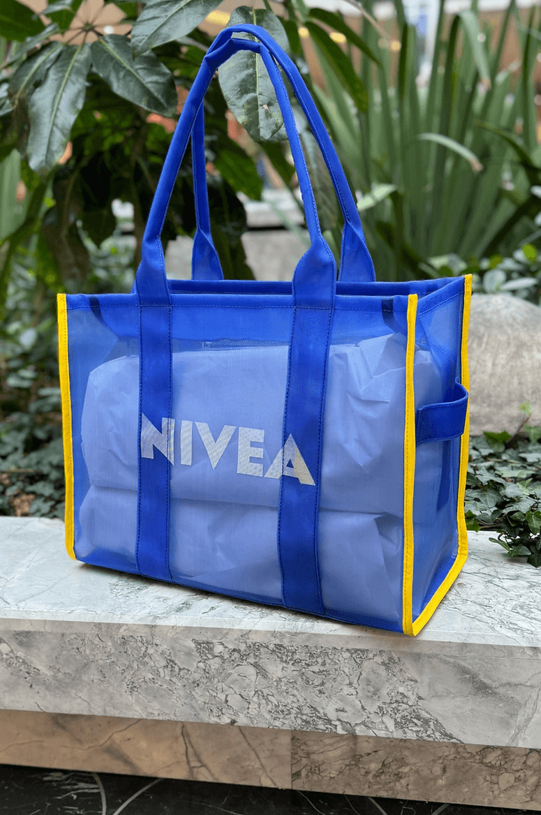 The Lux Micro Mesh Tote bag on a marble ledge next to some plants.