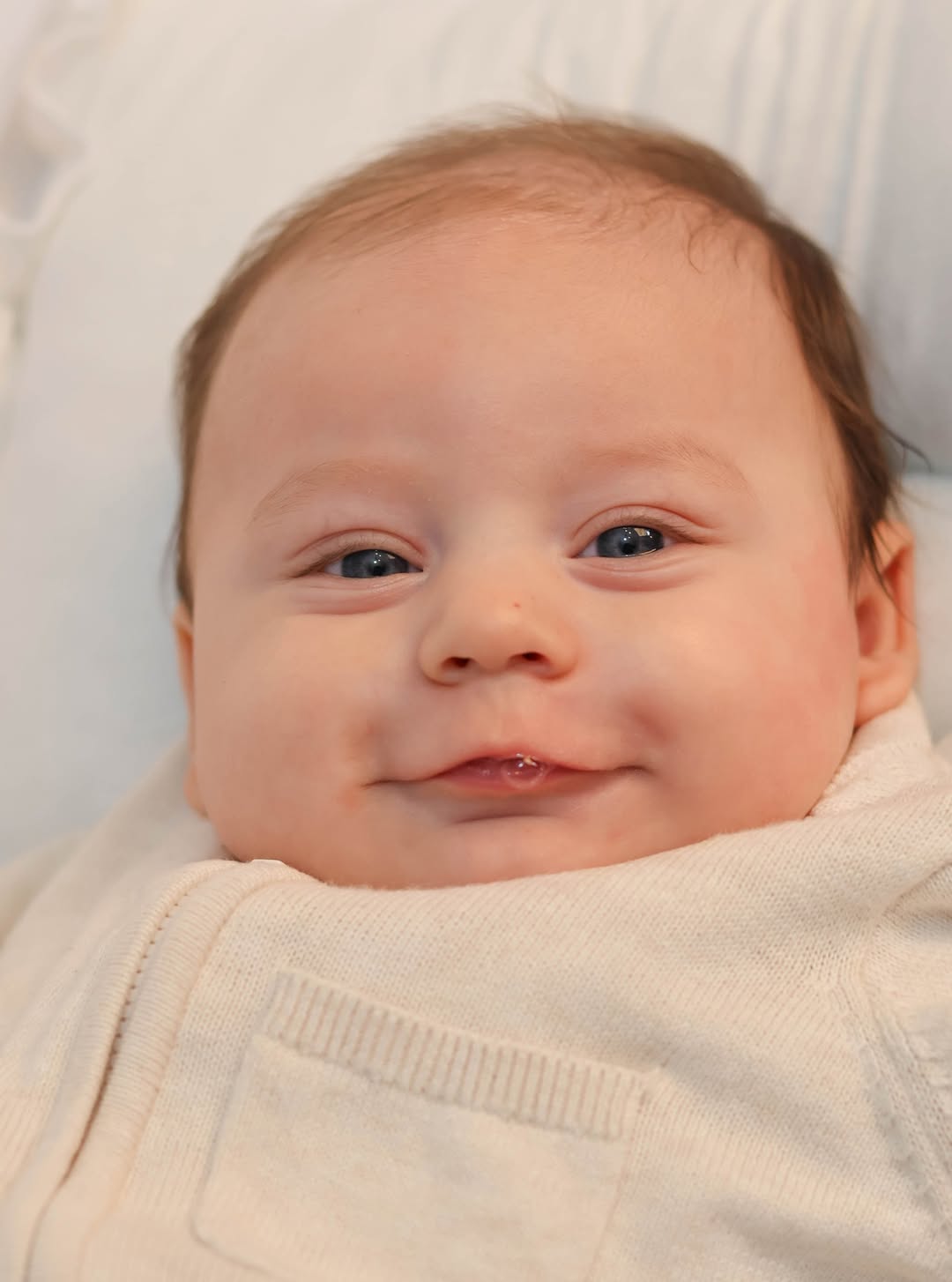 A couple in wedding attire walks hand in hand across a sunlit field.