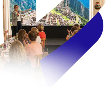 Apresentadora da Livare Viagens conduz a abertura oficial do Circuito Andino, com grupo de viajantes reunidos em auditório e imagem de Machu Picchu ao fundo no telão.