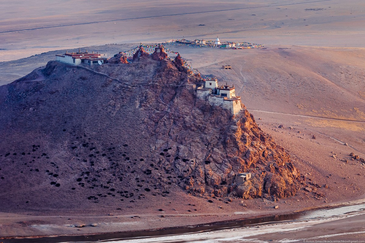 people walking on beach near brown concrete building under white clouds and blue sky during daytime