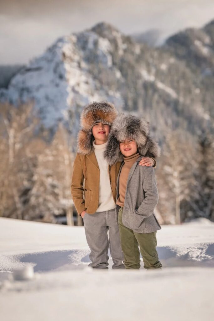 Children standing in the snow with mountain views at an Aspen family portrait location