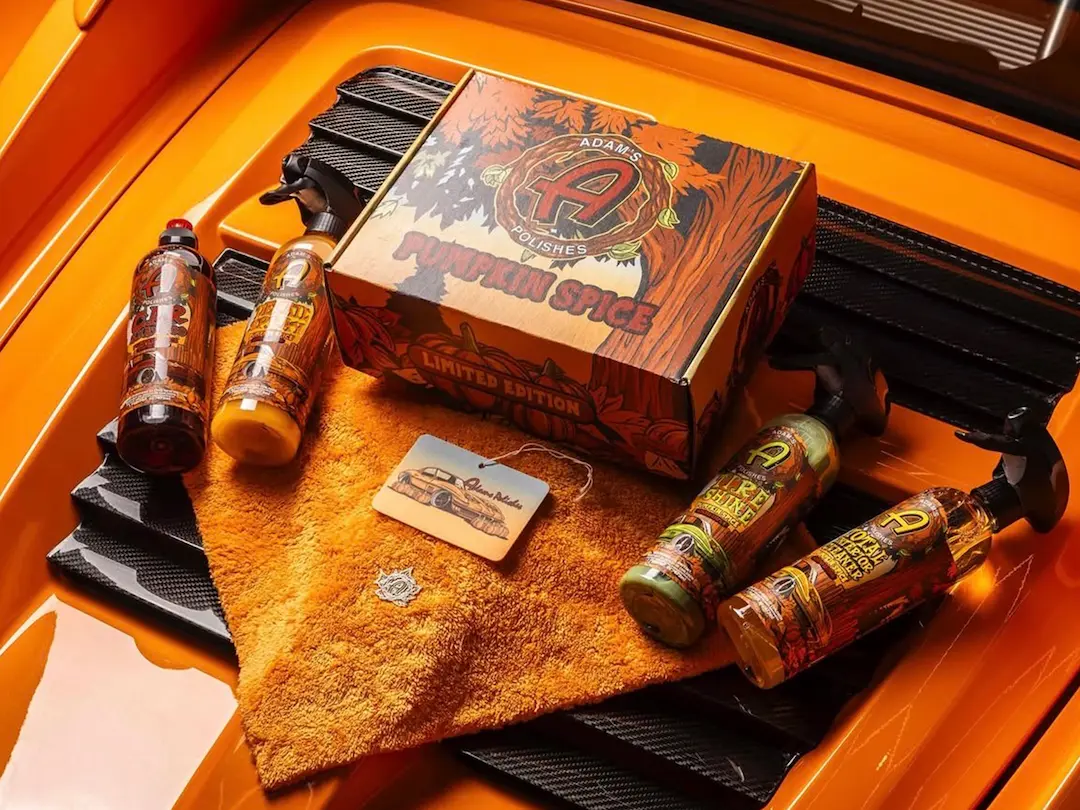 Adams Polishes summer edition car shampoo bottle displayed on a foam-covered car, featuring bright seasonal label design.