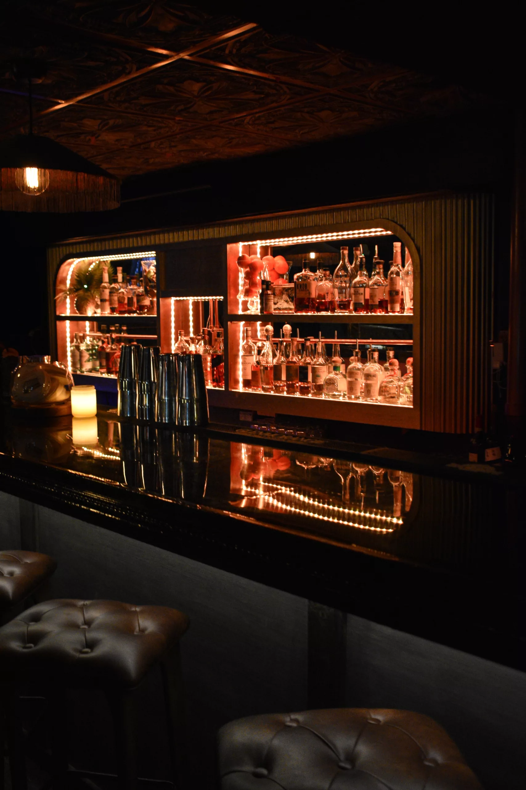 Dark speakeasy bar with mirrored, backlit shelves in Marmont at Forno Speakeasy, Forno Kitchen + Bar