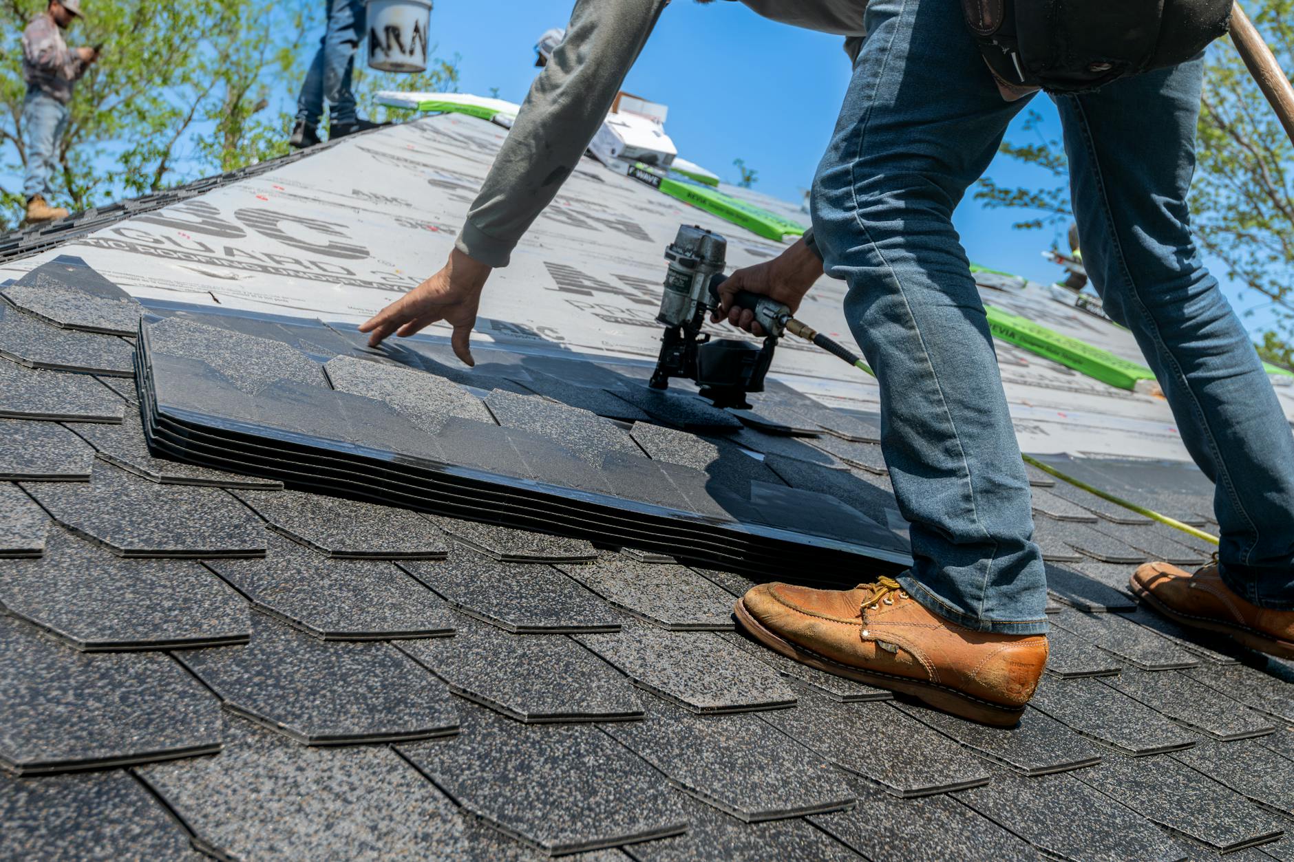 Roofer nailing asphalt shingles into place