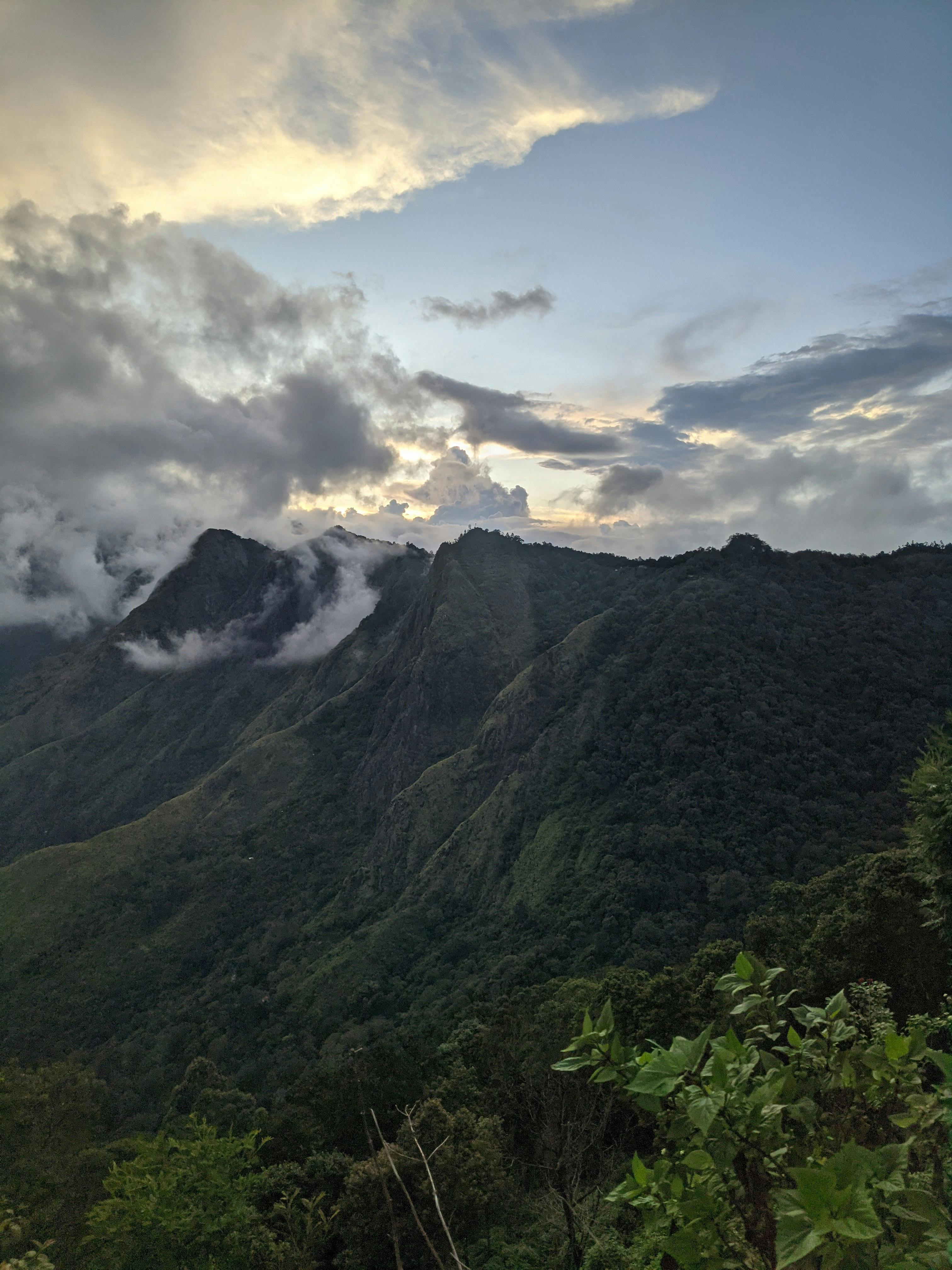 man standing near cliff looking at body of water during daytime