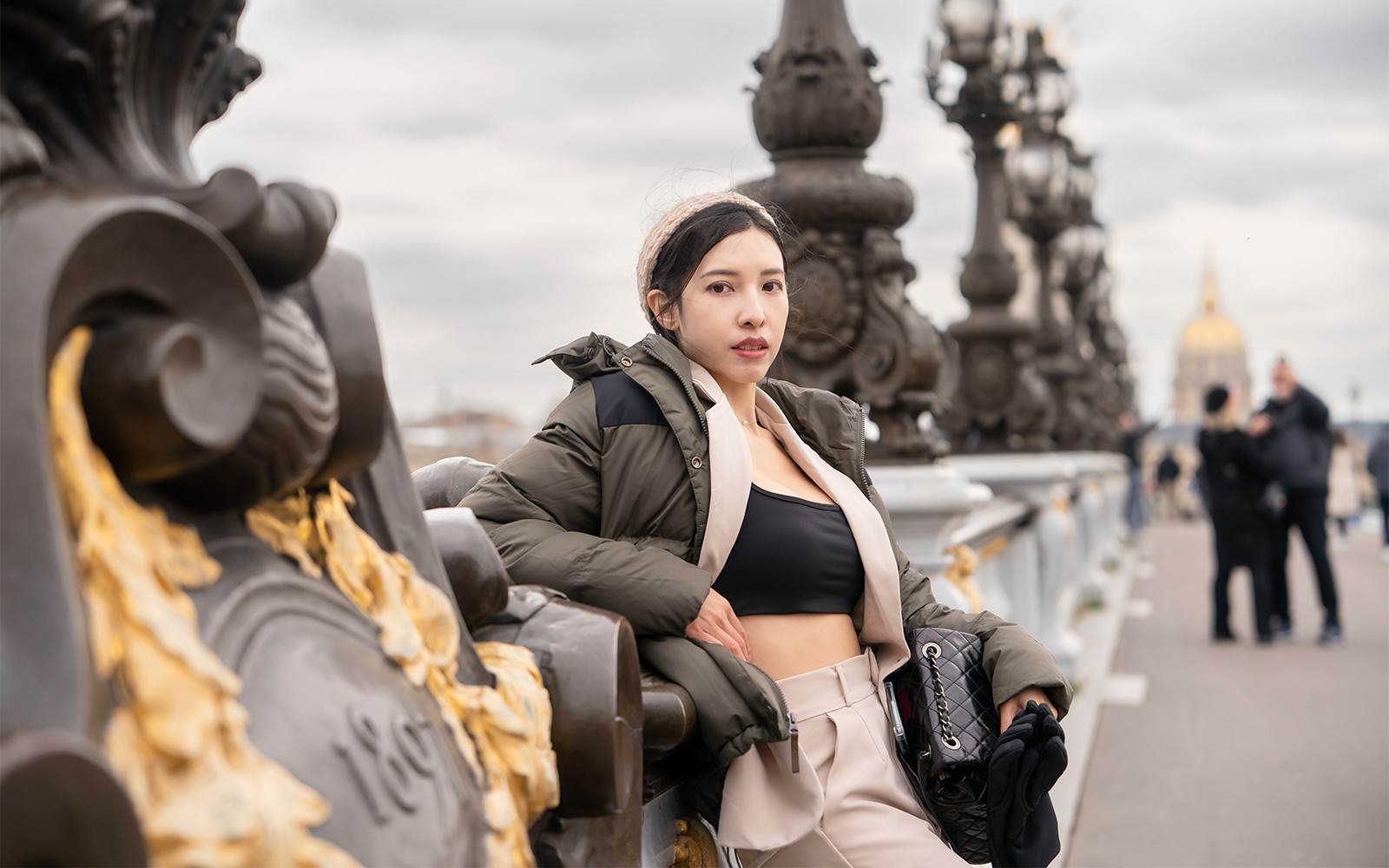 Persona posando en el puente Pont Alexandre III en París con farolas ornamentadas al fondo.
