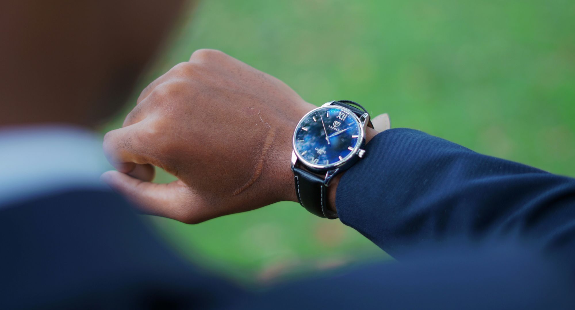 homem de paletó olhando as horas em seu relógio de pulso luxuoso