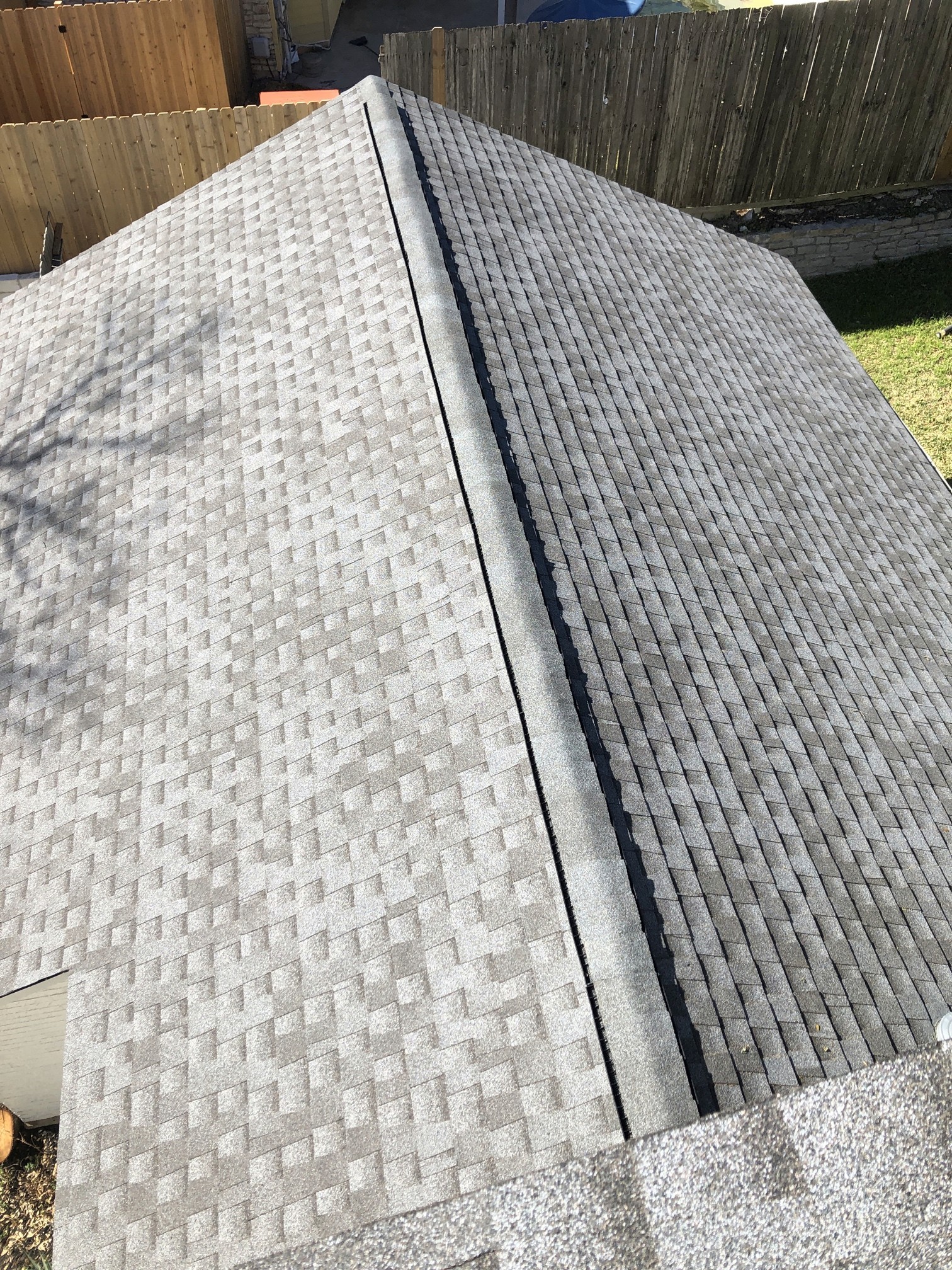 Gray architectural shingles and ridge caps viewed from above; illustrative roof detail, manufacturer not verified.