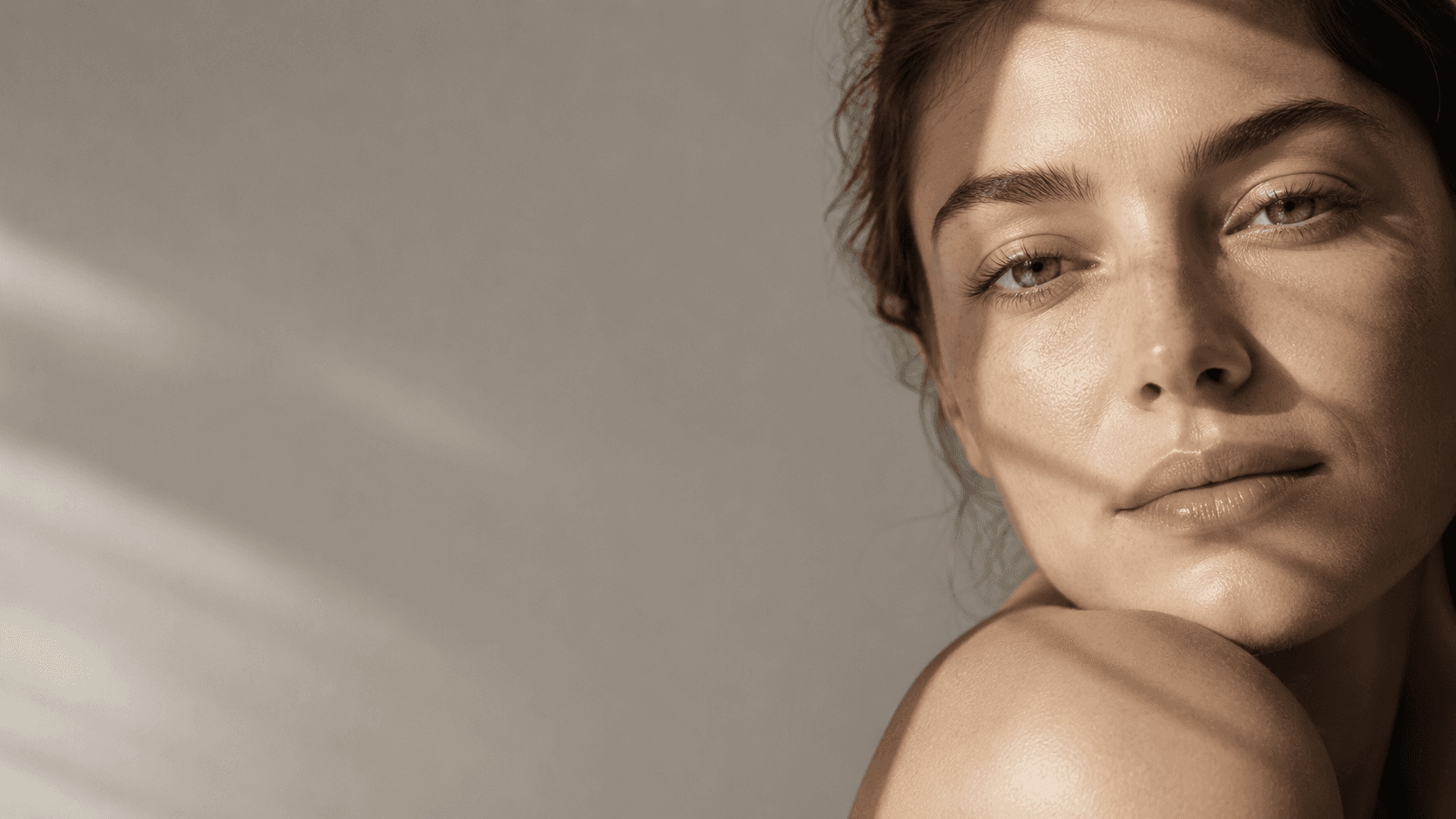 A close-up of a serene face illuminated by soft light, with shadows creating a patterned effect across the skin.