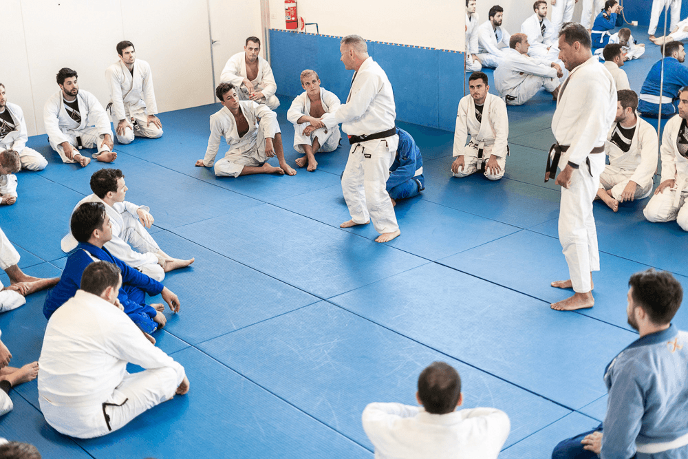 Two adults practicing ground techniques in a Jiu Jitsu class