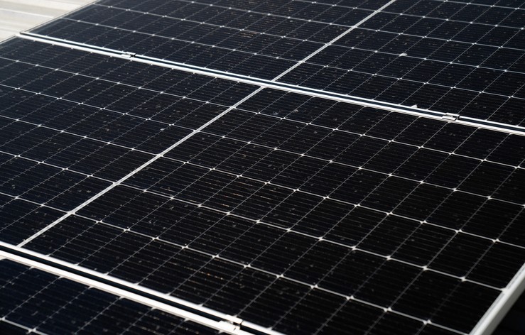 Nahaufnahme von Solarpaneelen mit einer eleganten, dunklen Oberfläche, die unter natürlichem Licht in einem Rastermuster angeordnet sind.