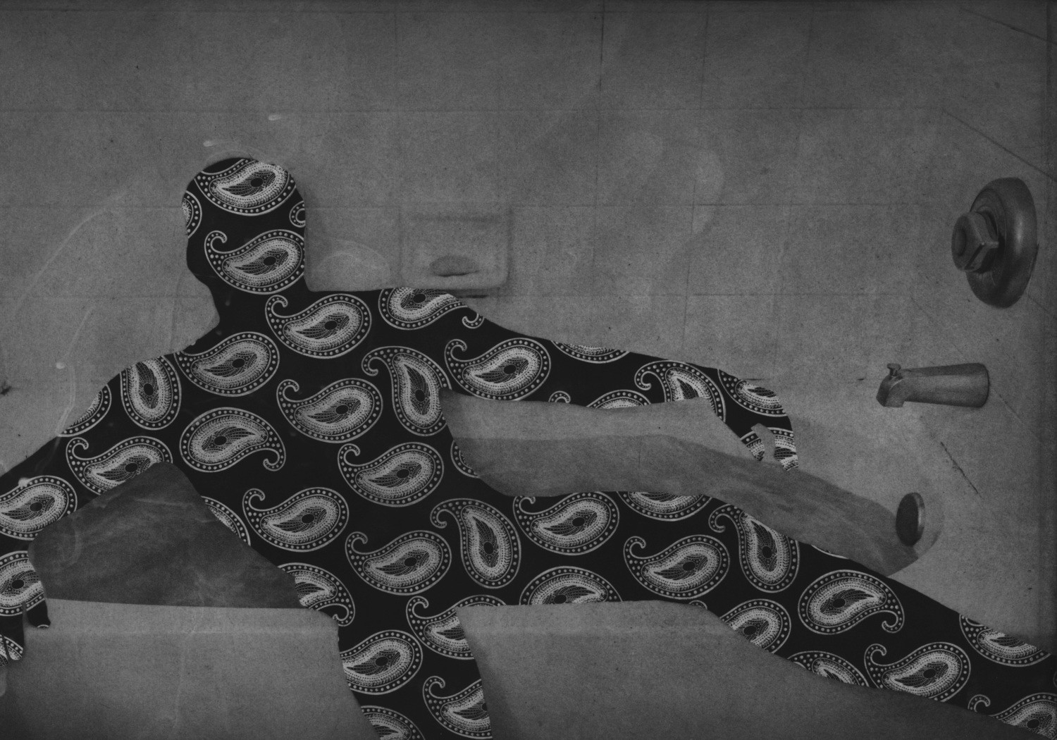 Photogravure print depicting a reclining human silhouette filled with a repeating paisley pattern against a monochromatic bathroom setting, blending photographic imagery and graphic texture to create a surreal exploration of form, identity, and spatial contrast.