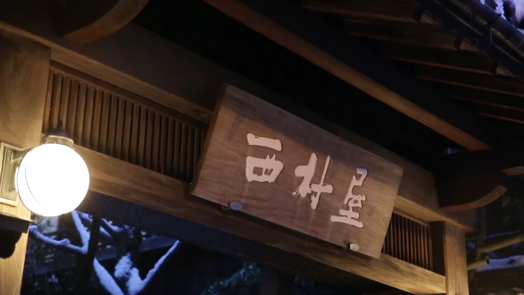 The carved name board of Nishimuraya Honkan mounted above its entrance in Kinosaki.
