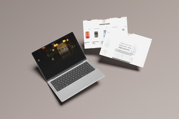 Ein Laptop und zwei lose Blätter zeigen das Design der neuen Brauhaus-Website mit Bierprodukten und individueller Biergestaltung.