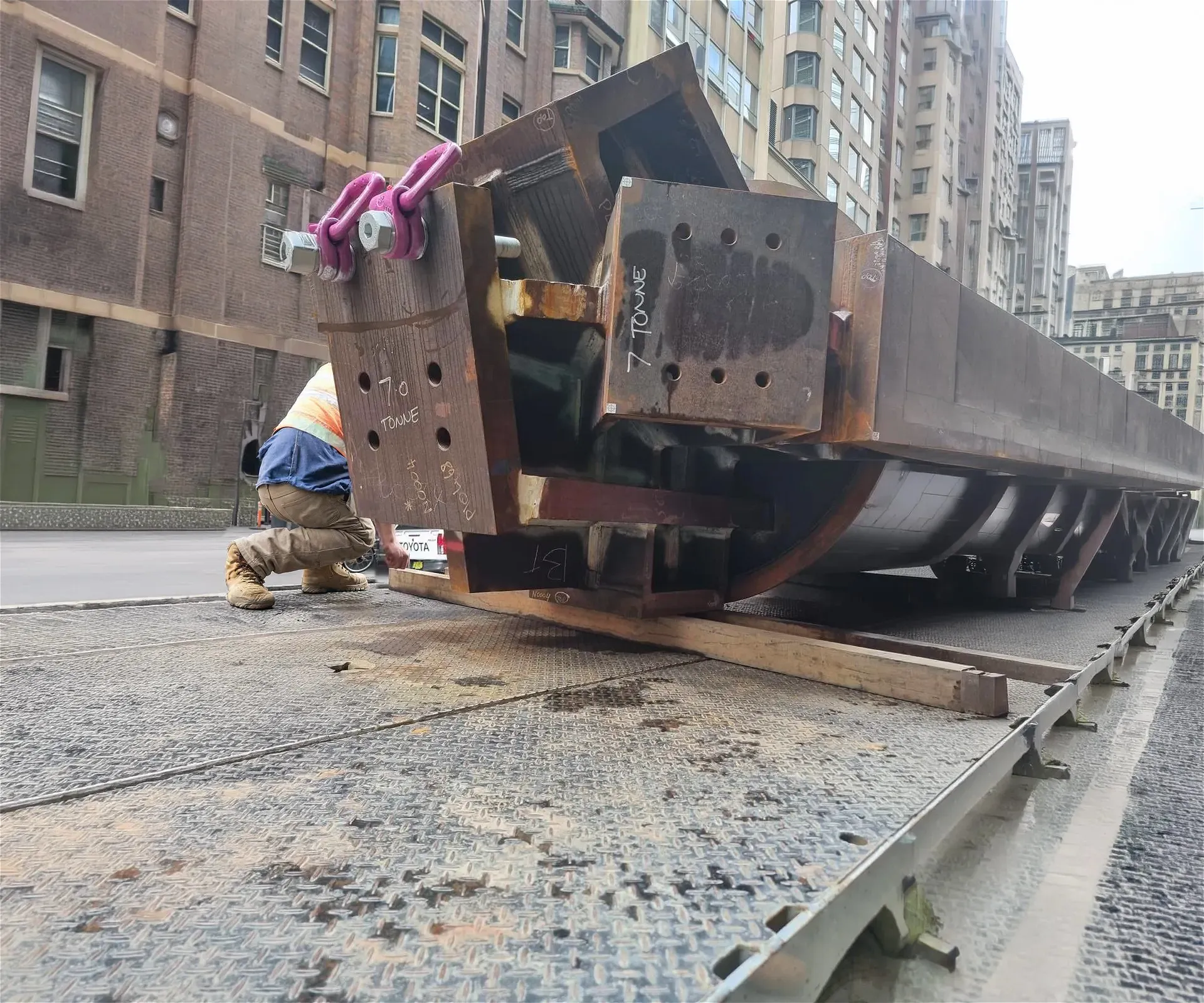 Large steel beams labeled "7 tonne" on a flatbed truck.