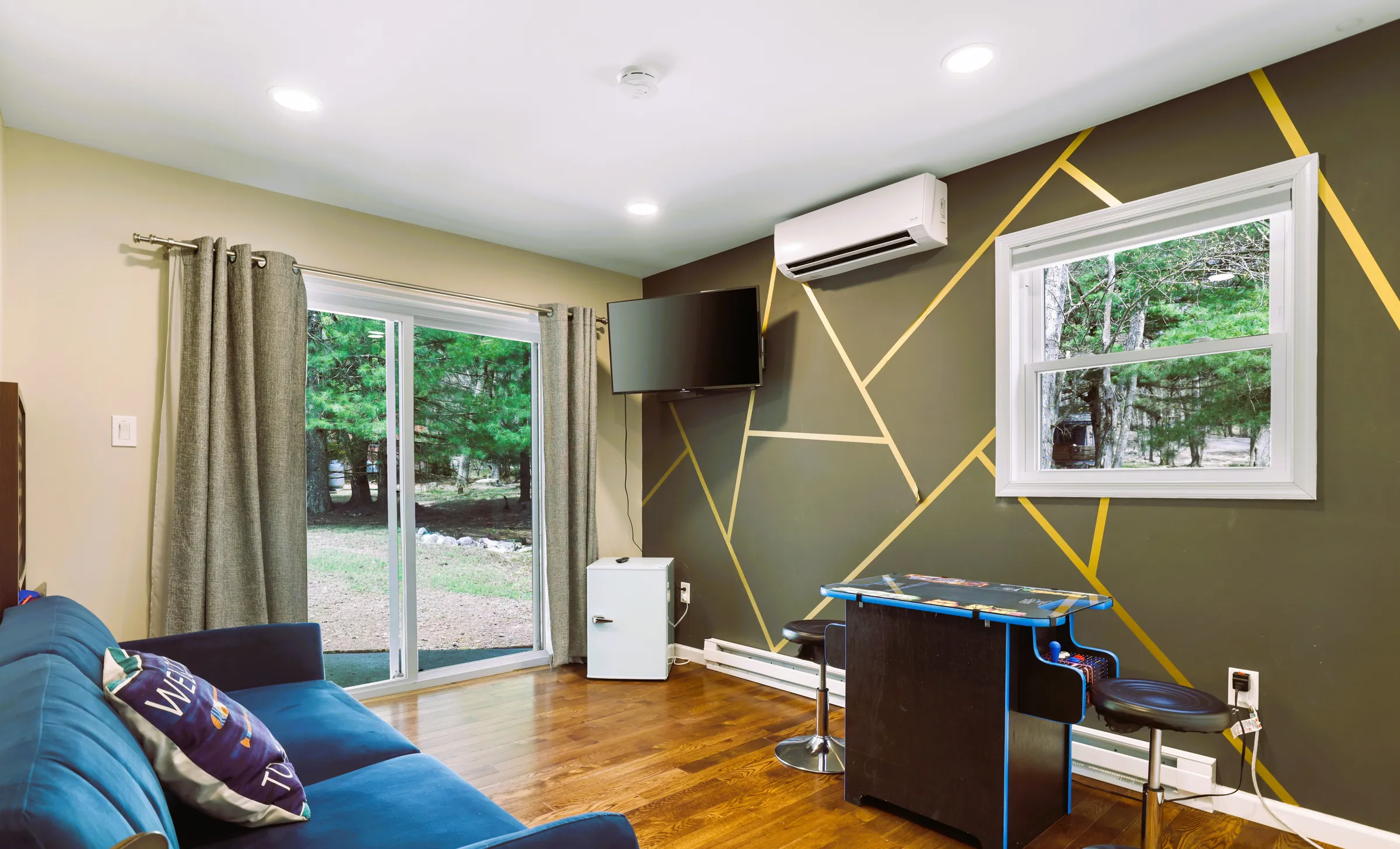Lounge with blue sofa, arcade table and geometric accent wall at Divine on Lupine