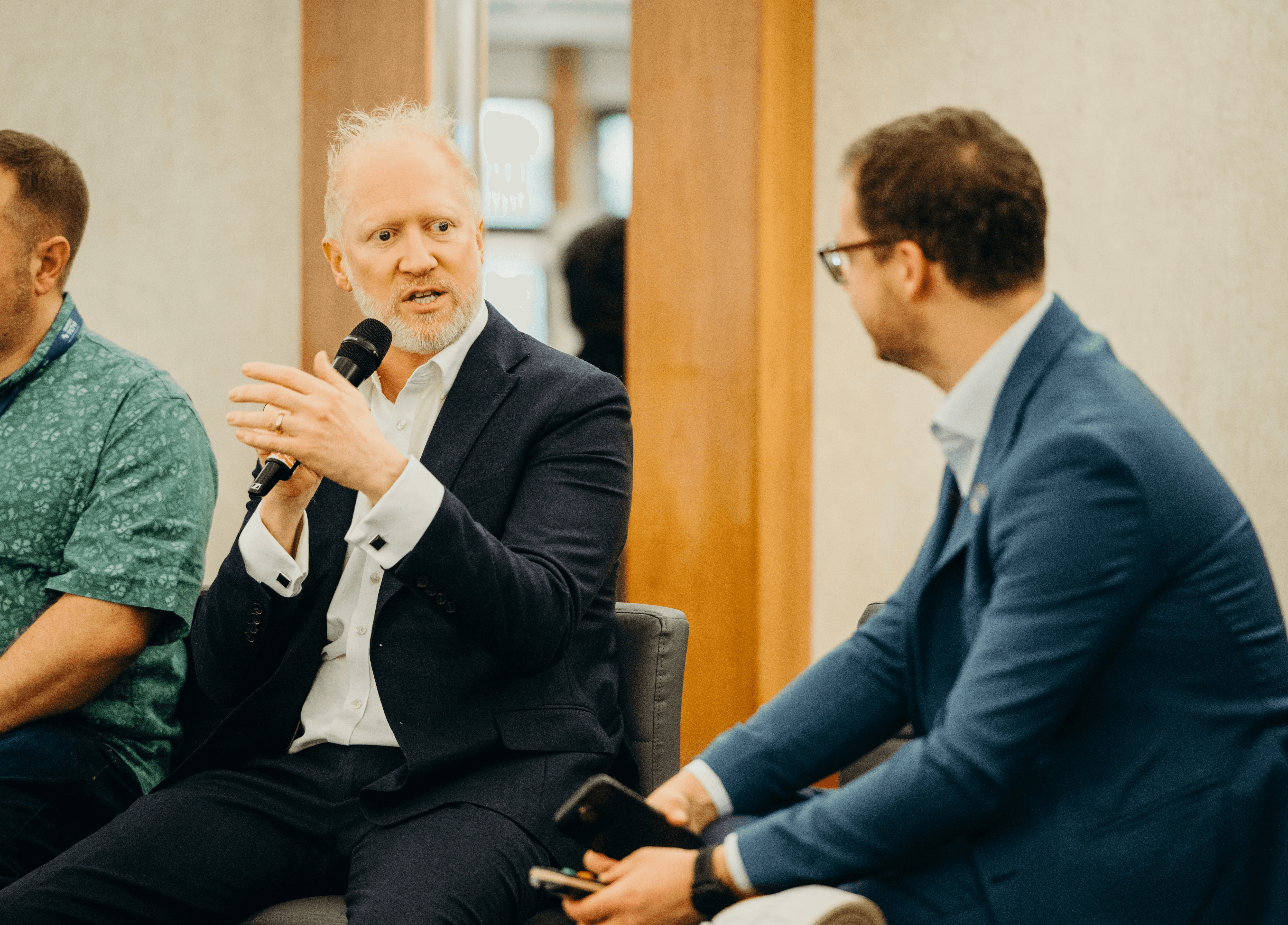 Simon Zutshi: Man with grey beard holding microphone while speaking at property investment event