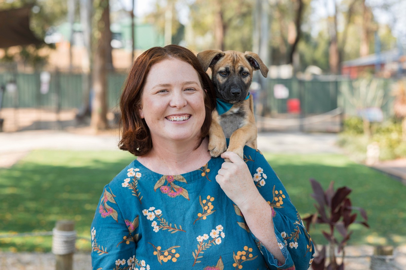 Woman in turquoise dress with puppy on shoulder