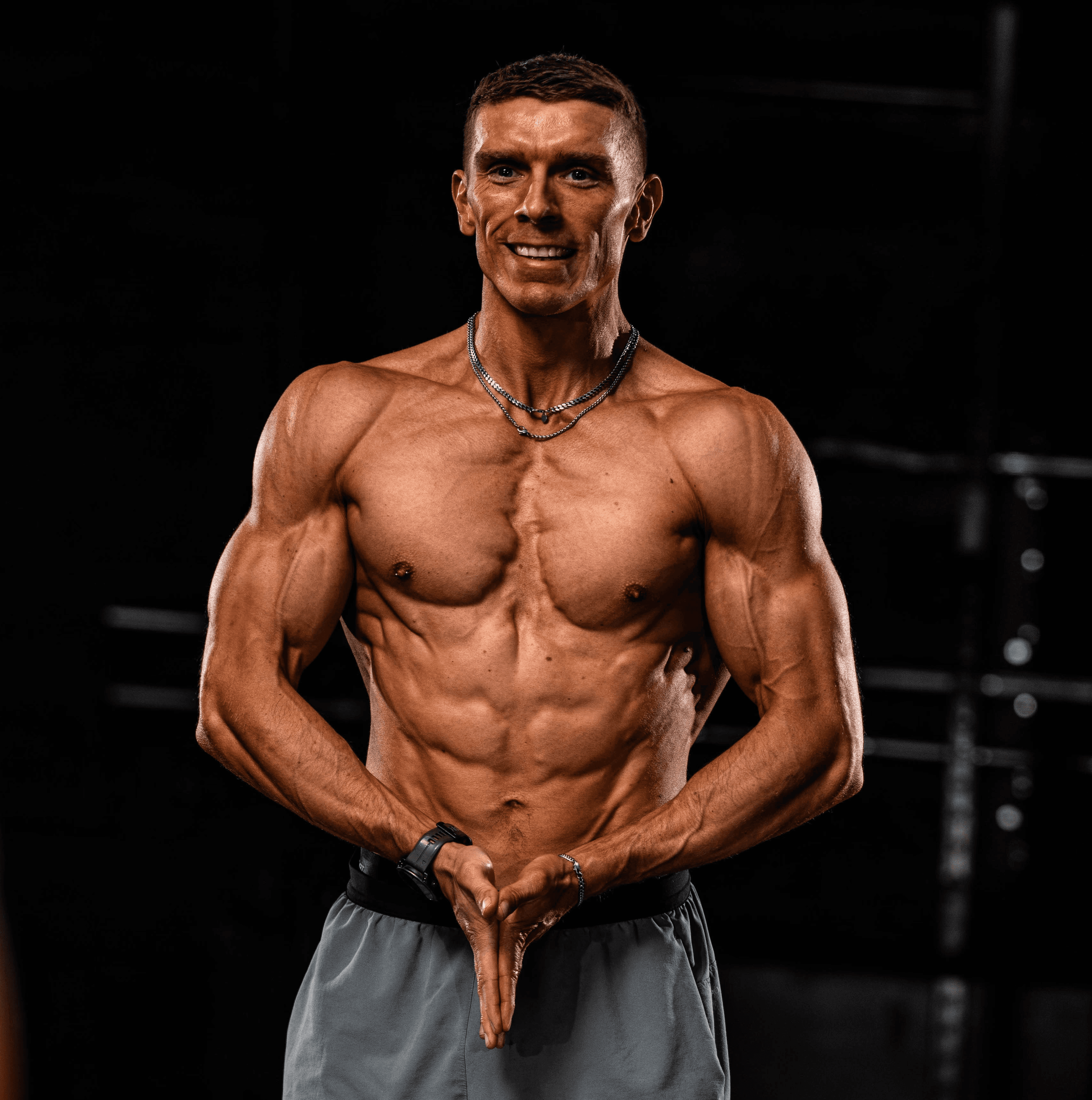 A personal coach lifts a heavy barbell in a dimly lit gym, focusing intently on the task.