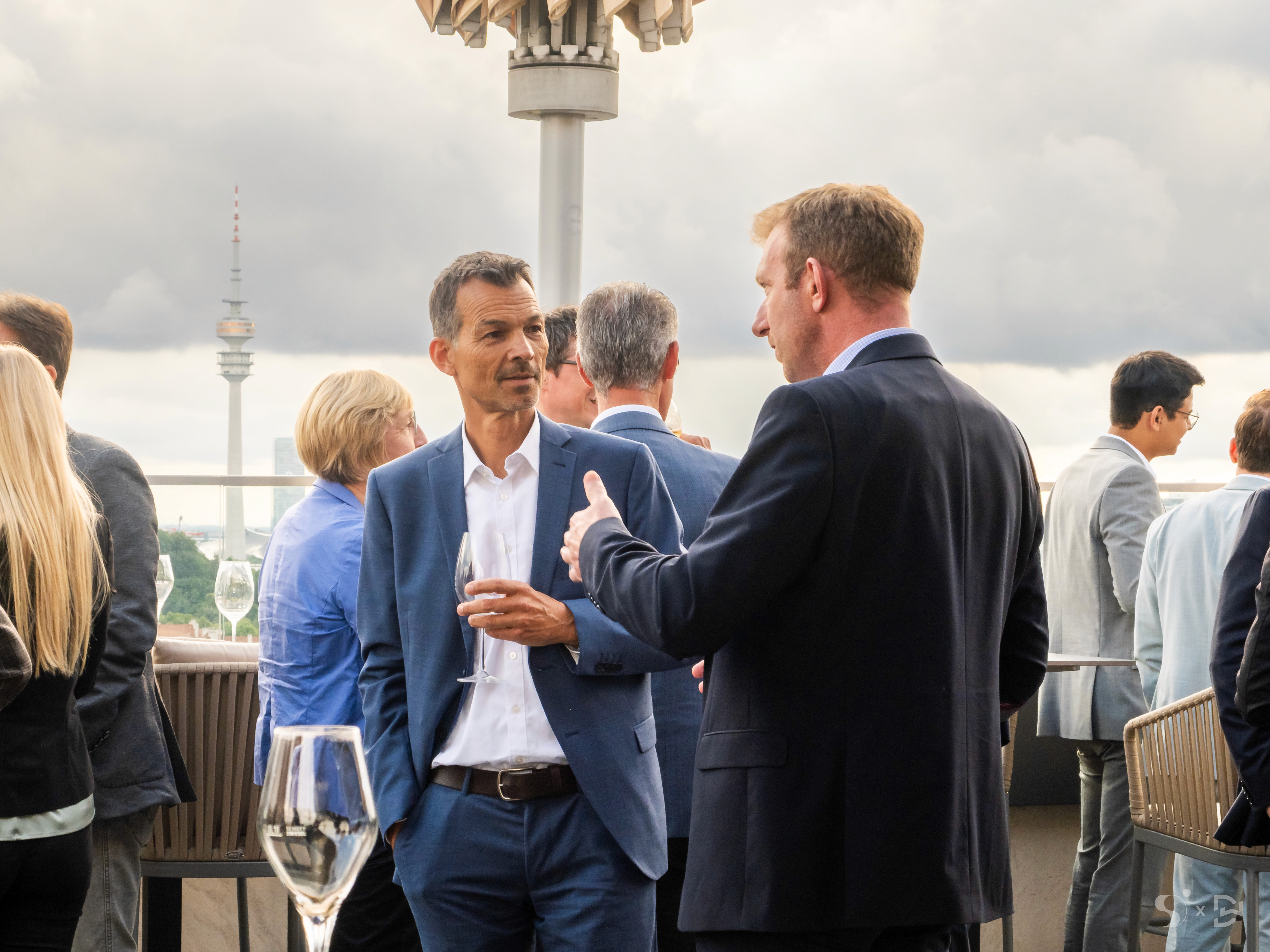 Teilnehmer des Bayerischen Immobilienkongresses im Gespräch auf der Dachterrasse mit Blick über München