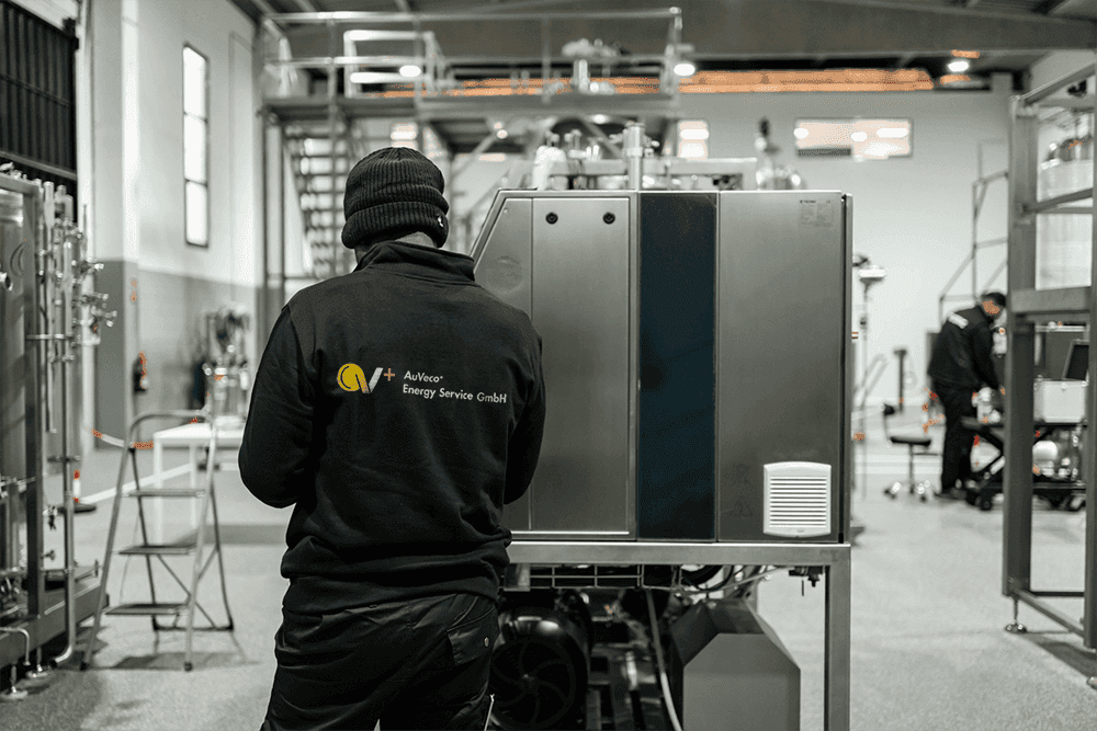 Ein Mitarbeiter betrachtet aufmerksam eine Maschine in der Produktionshalle.