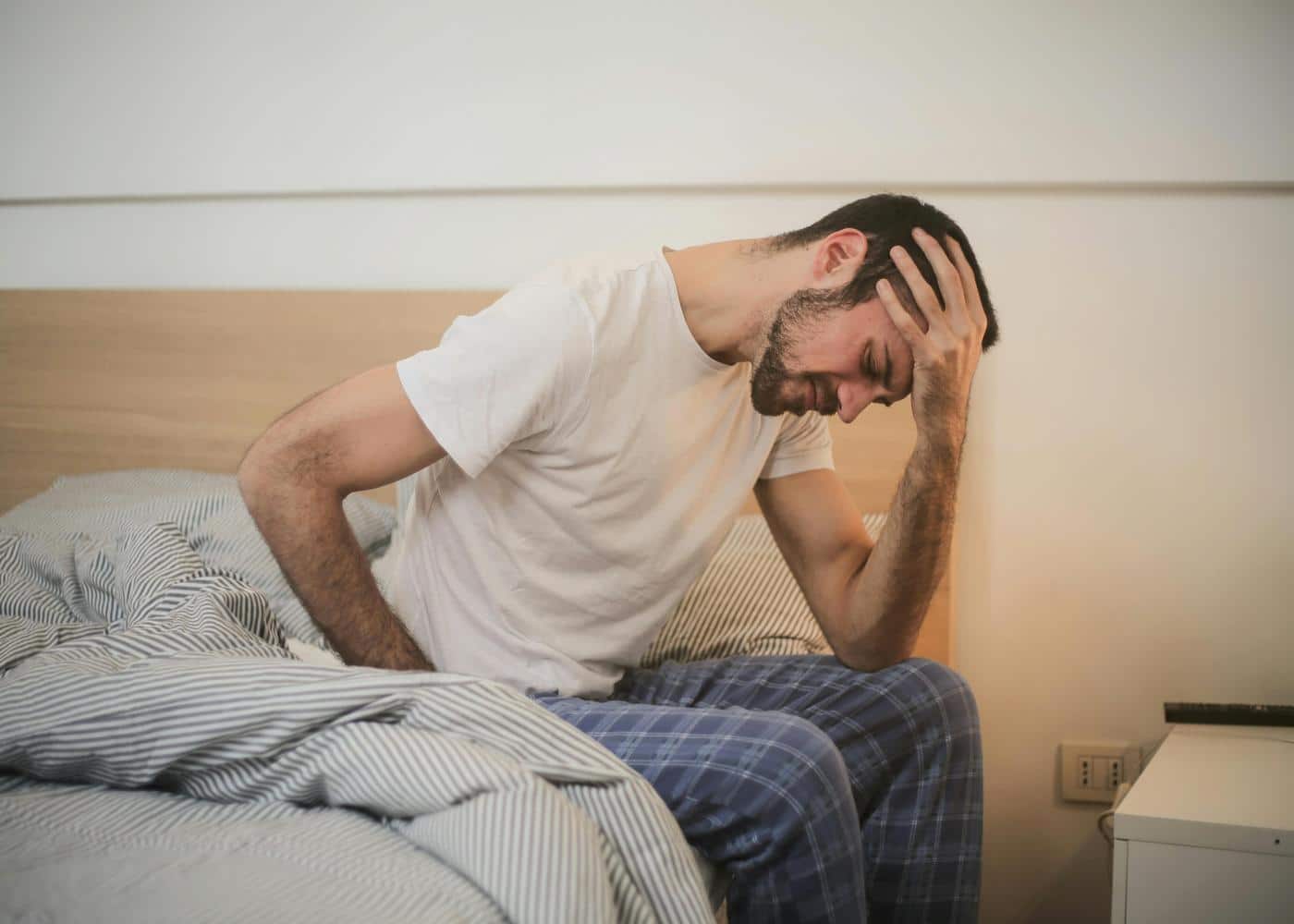 Low testosterone signs - man sitting slumped on edge of the bed