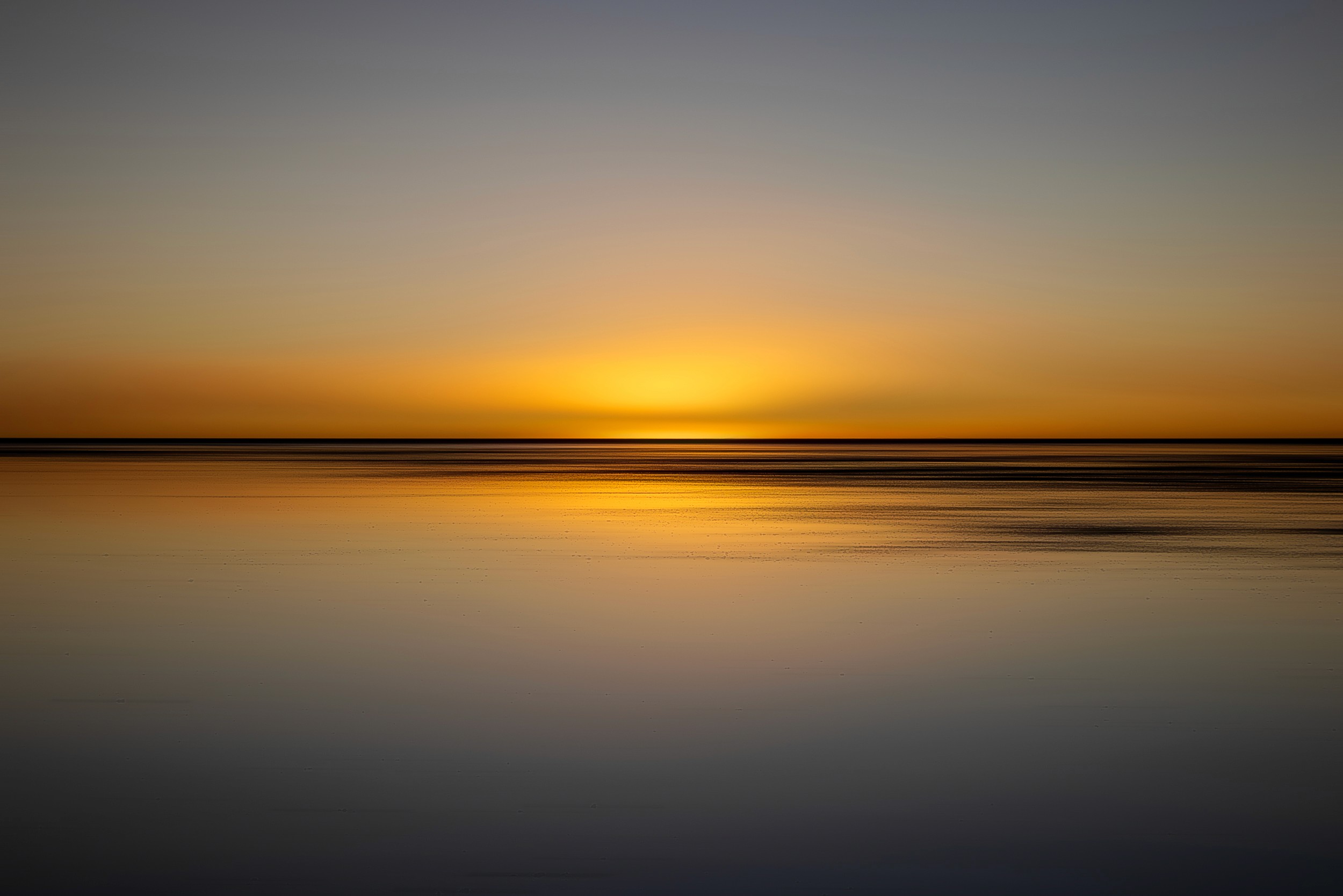 Golden sunset reflected across still water, creating a mirror-like abstract landscape in soft gradients
