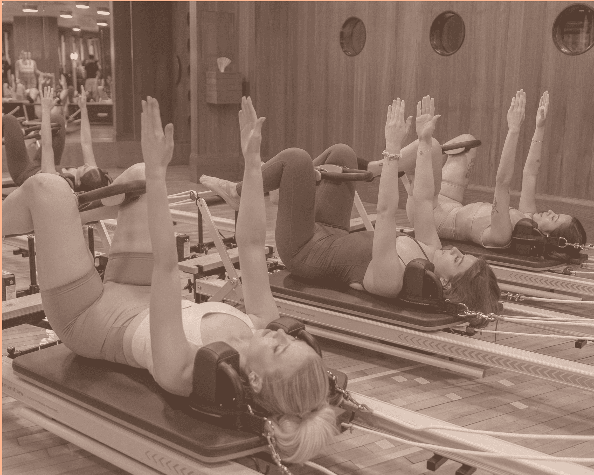 Three people doing pilates in a reformer machine with a pilates ring.