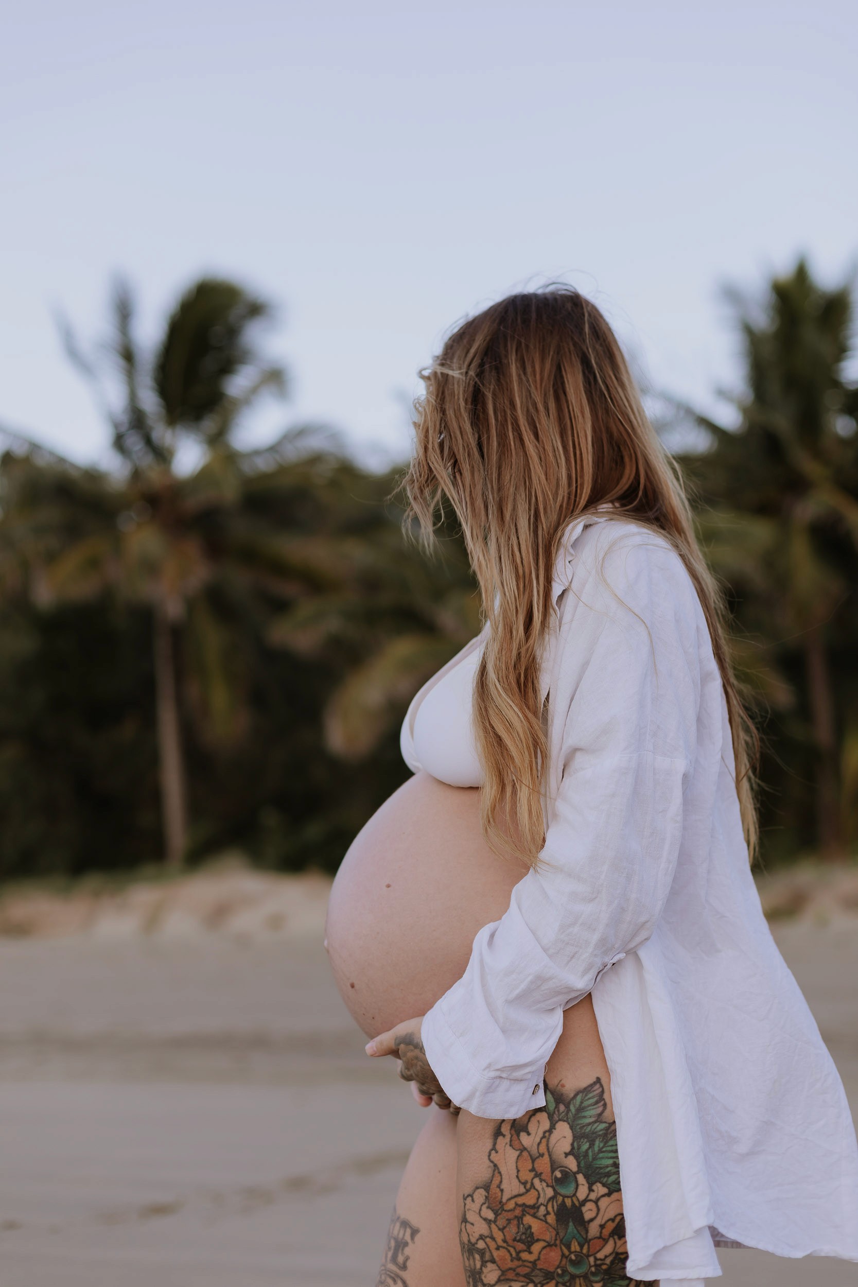 Expecting mother embracing her pregnancy at sunrise on Mackay coastline