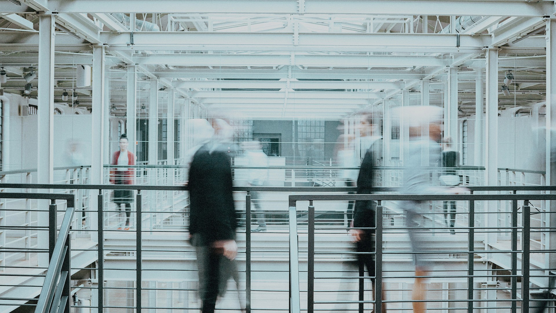 A motion blur and grainy image of people walking in an office.