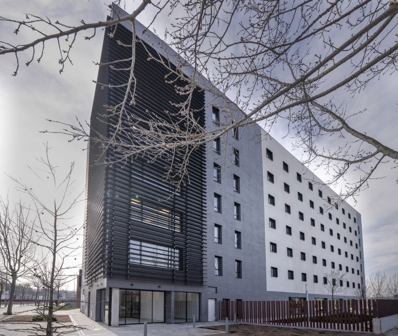 Modern building exterior featuring dark horizontal louvers and a white geometric facade.