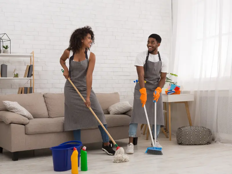 Two cleaners mopping and sweeping a bright living room