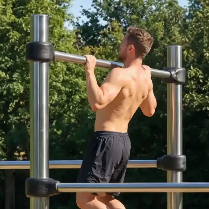 man trekt zich op aan horizontale bar van fitness toestel, outdoors