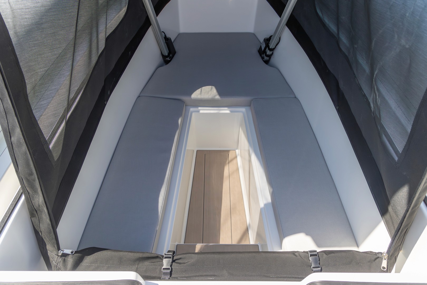 Modern yacht cabin entrance with glass window looking down into bright interior spaces with wooden flooring.